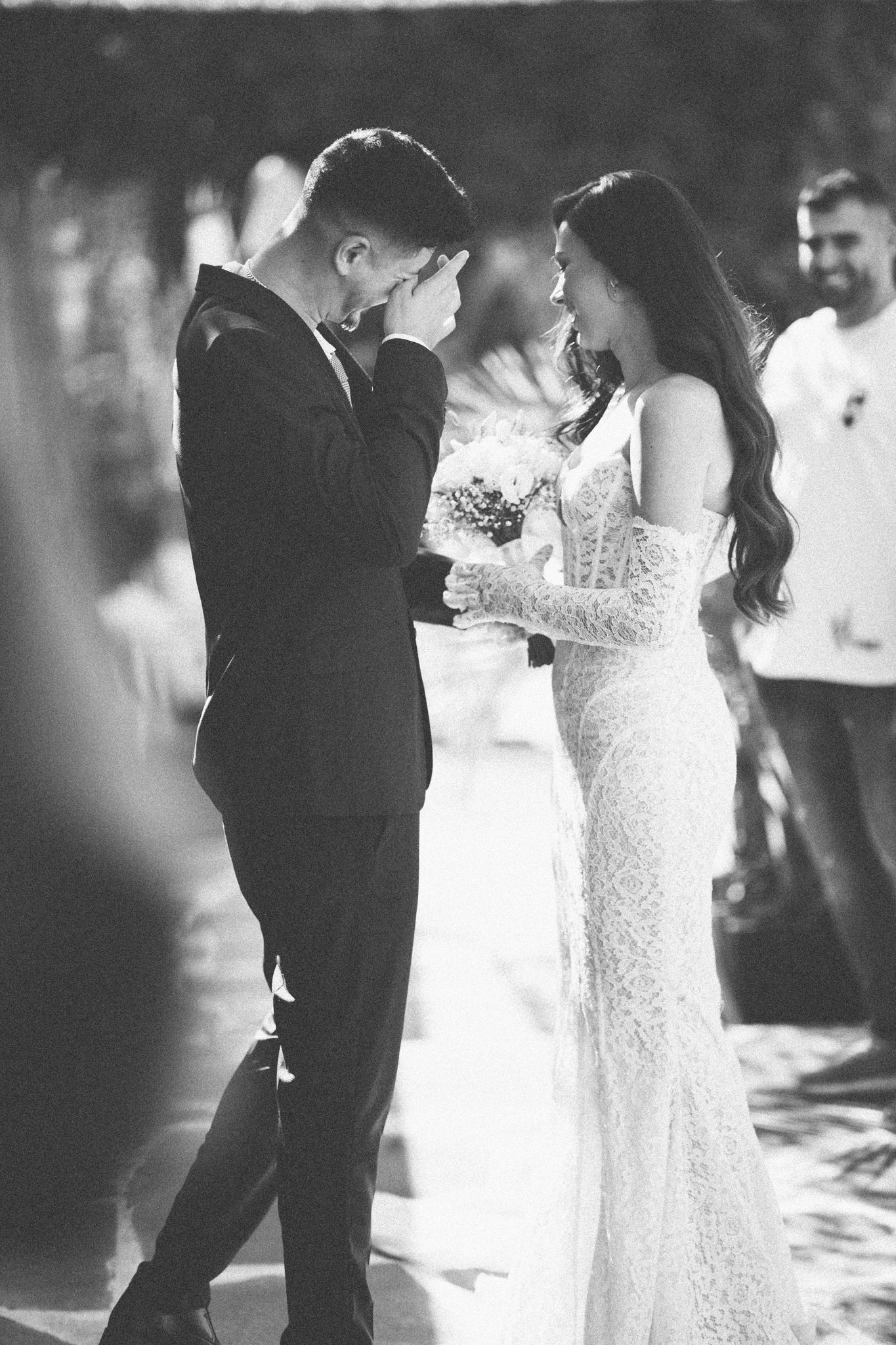Black and white emotional moment during wedding ceremony with bride in lace gown.