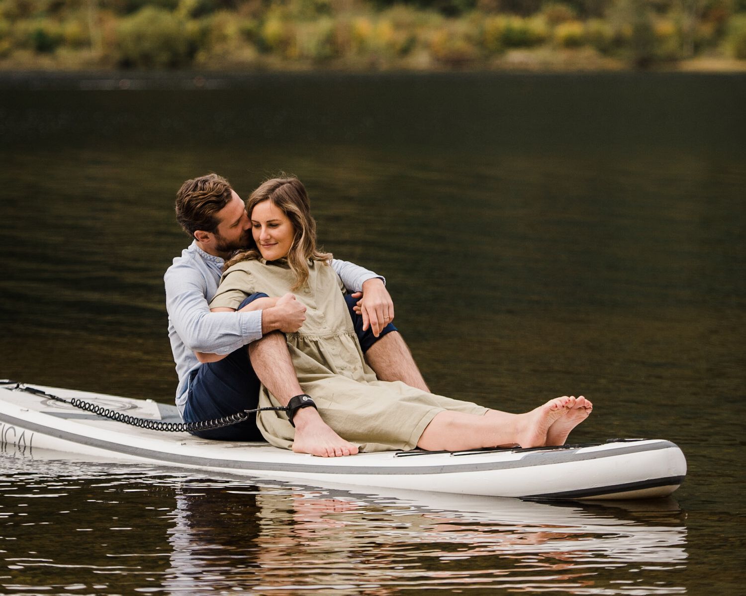 Couple embracing on paddle board SUP on a lake in the Scottish Highlands.