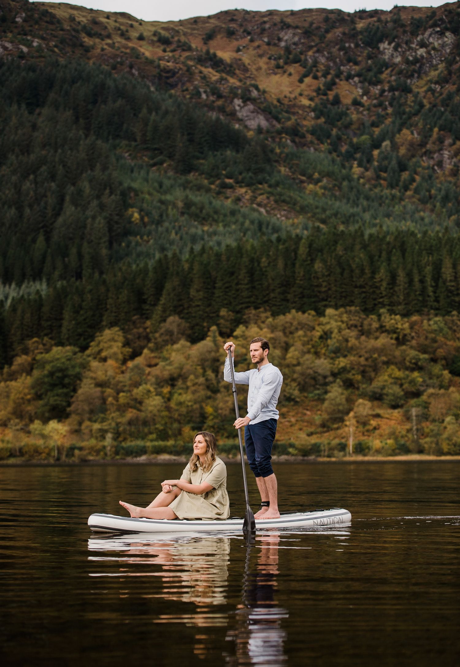 Couple on paddle board SUP on a lake in the Scottish Highlands.
