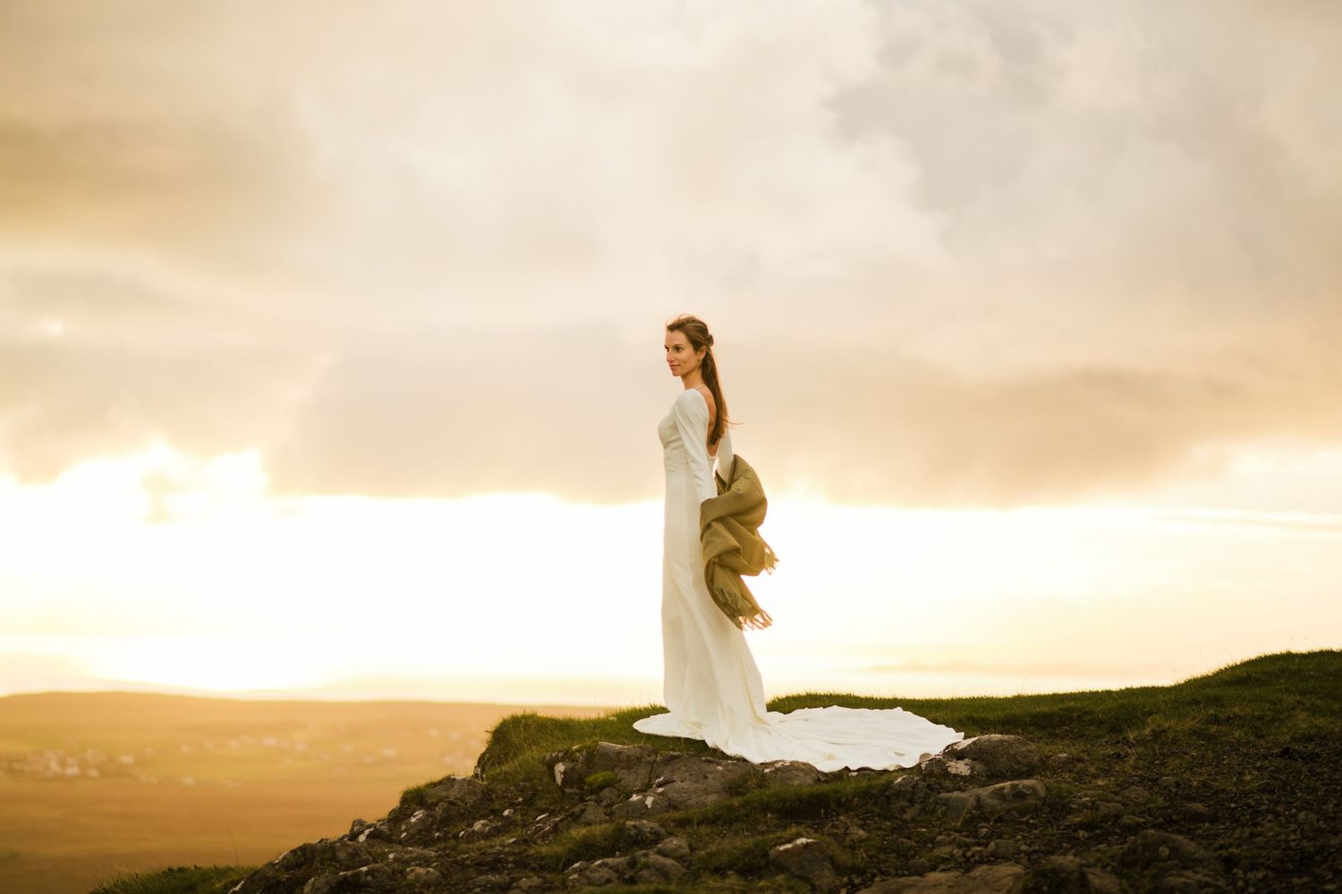 Bride on top of a cliff in Scottish Highlands' elopement at sunrise.