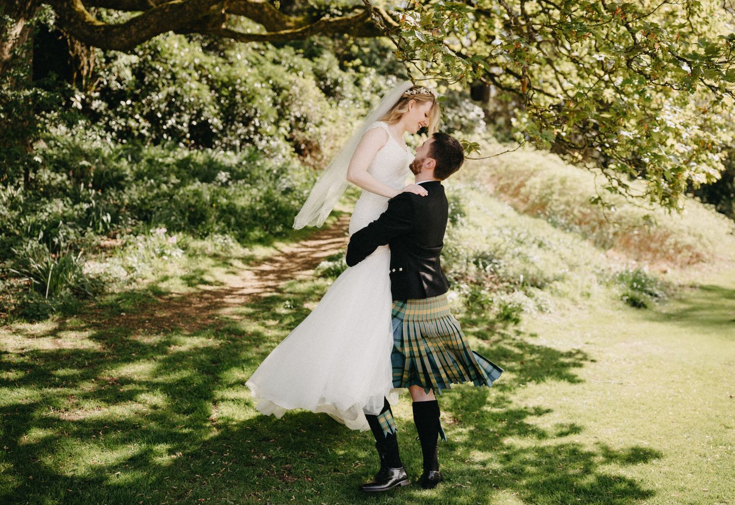 Groom lifting bride in the countryside during Scottish castle wedding.
