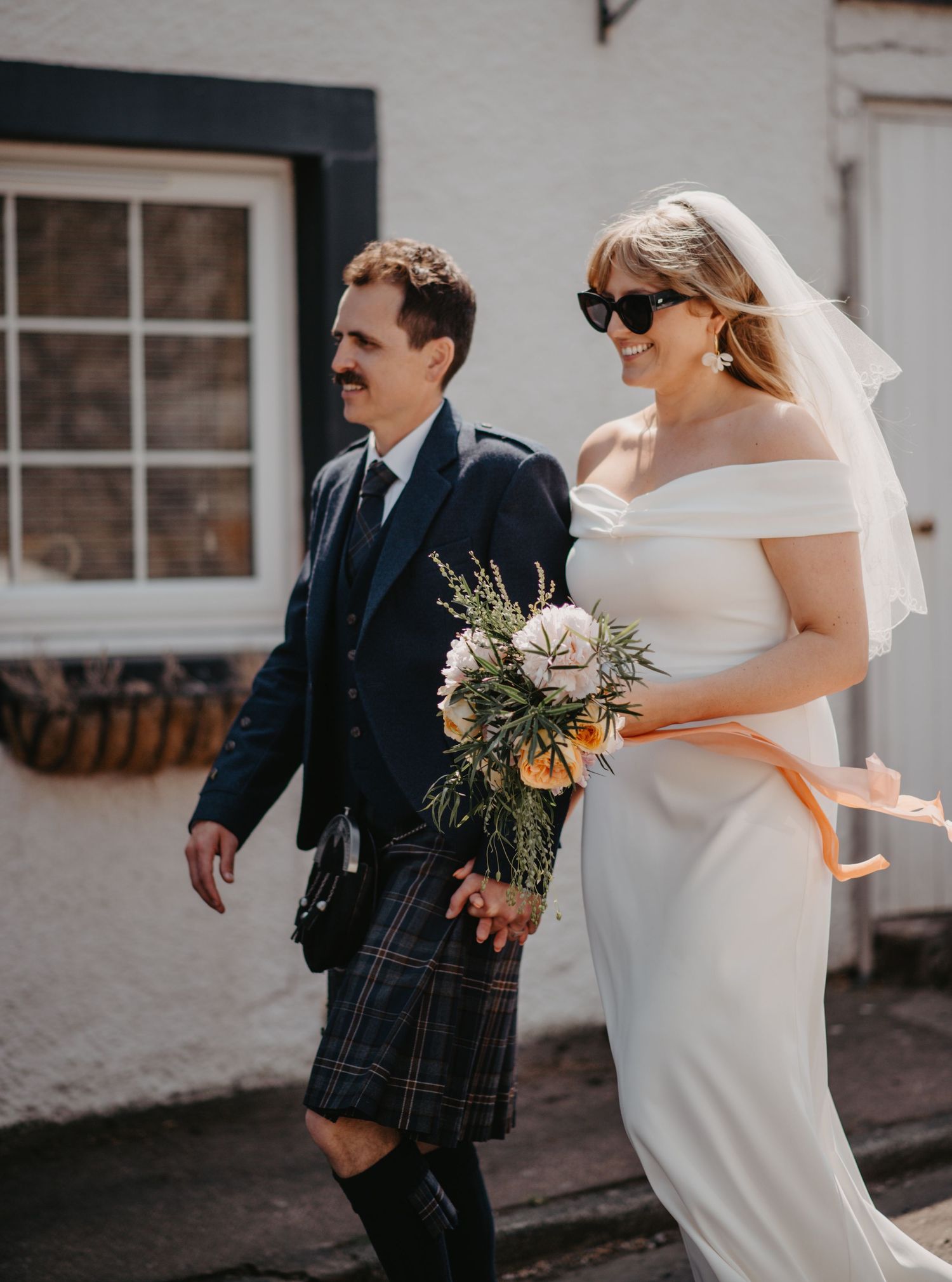 Bride and groom walking down the street at countryside wedding in Scotland.
