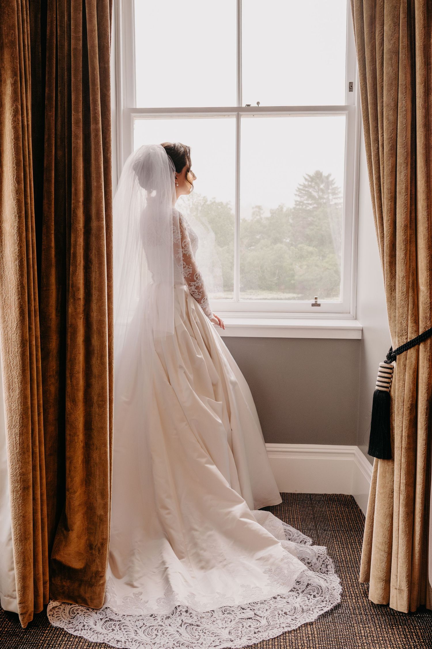Bride in veil looking out the window during Scottish castle wedding.