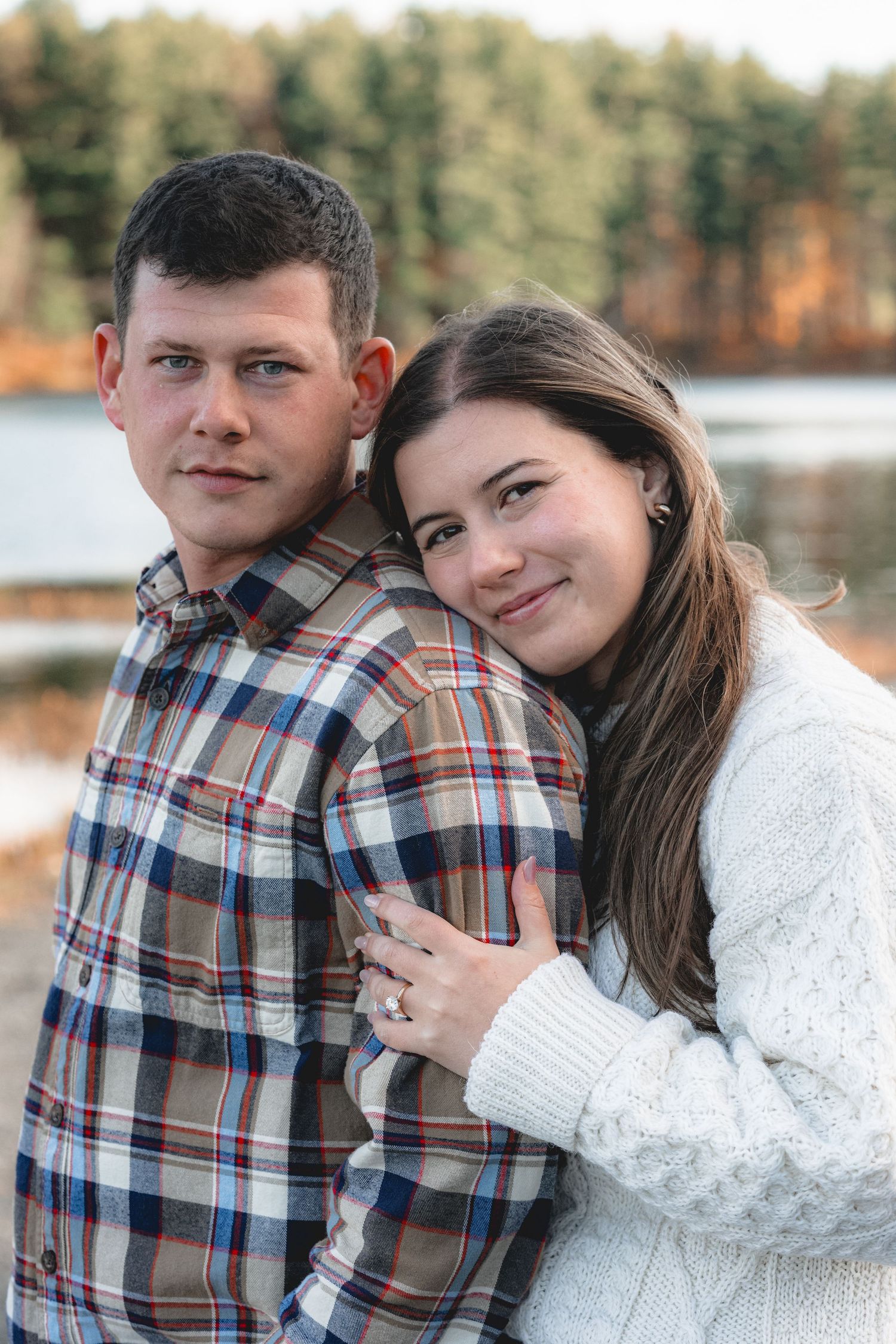 A couple in plaid and white sweaters share intimate moments outdoors during an autumn photoshoot.