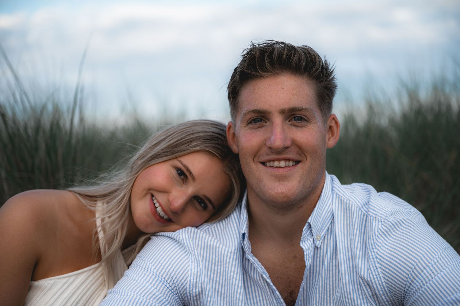 Couple sharing tender moments together in a grassy field during a sunset photoshoot.