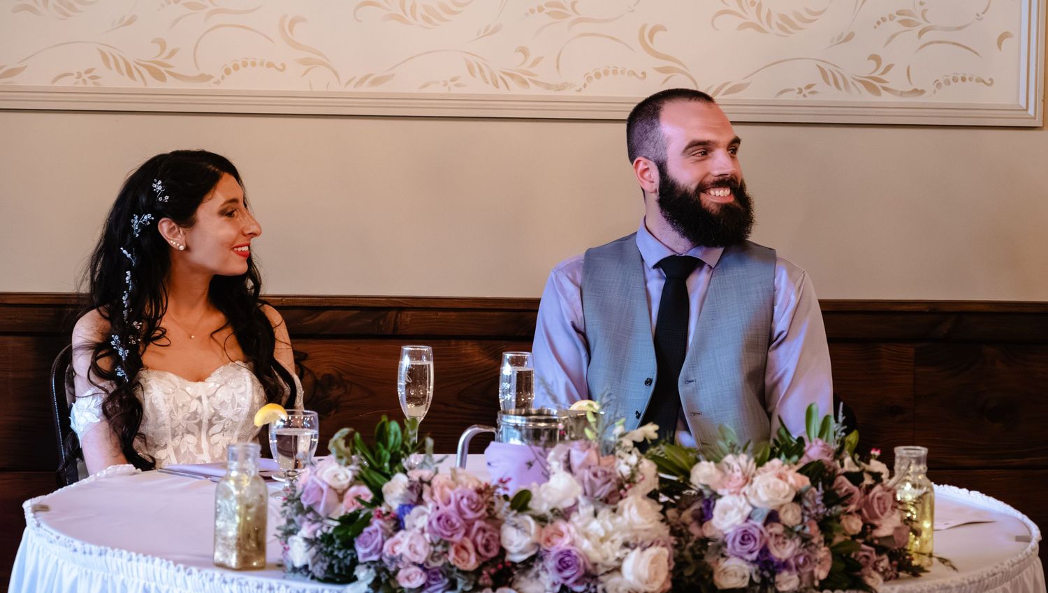 Wedding reception table decorated with purple and pink floral centerpieces.