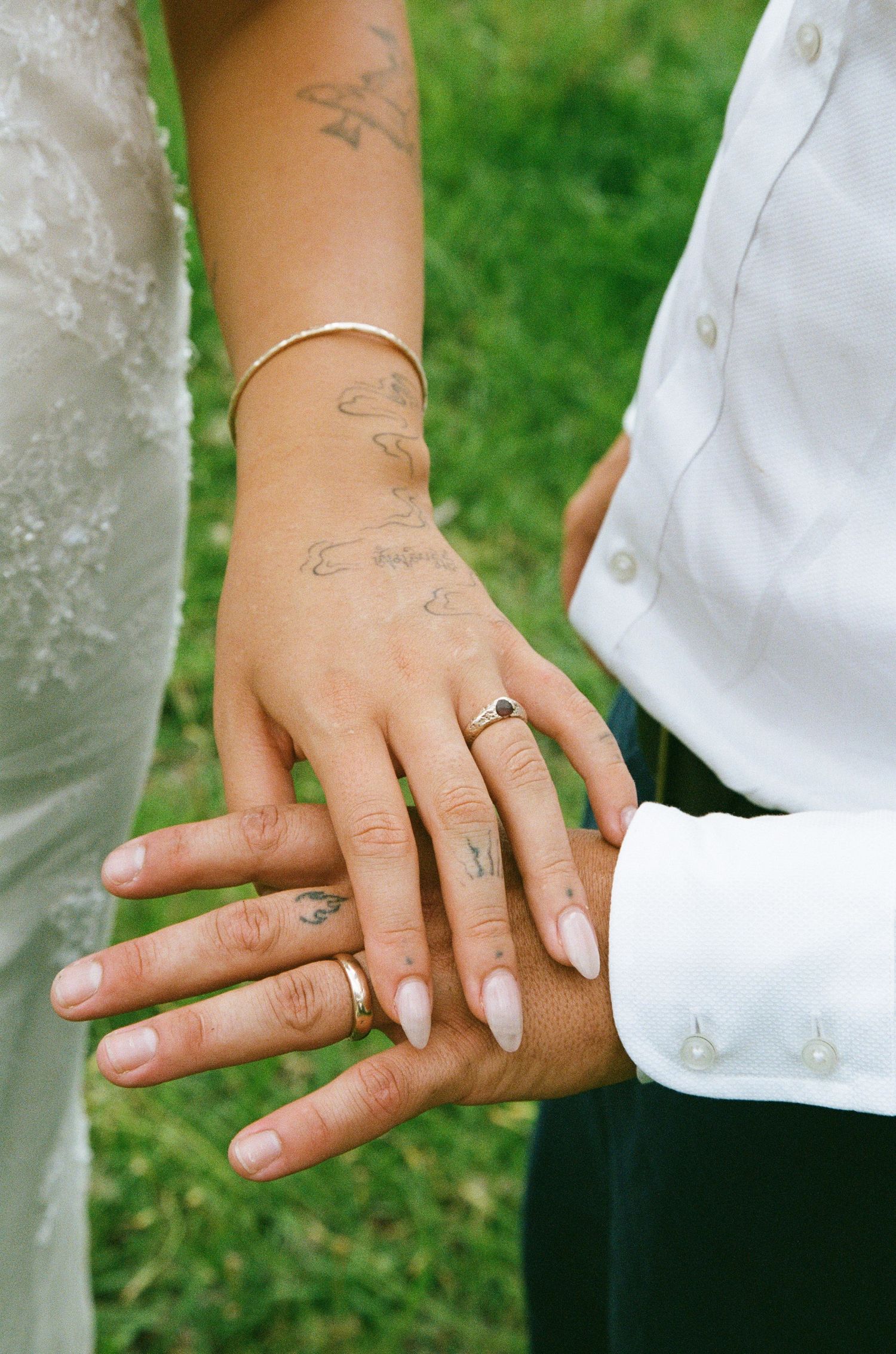 Close-up shots of hands displaying engagement rings against a green garden background.