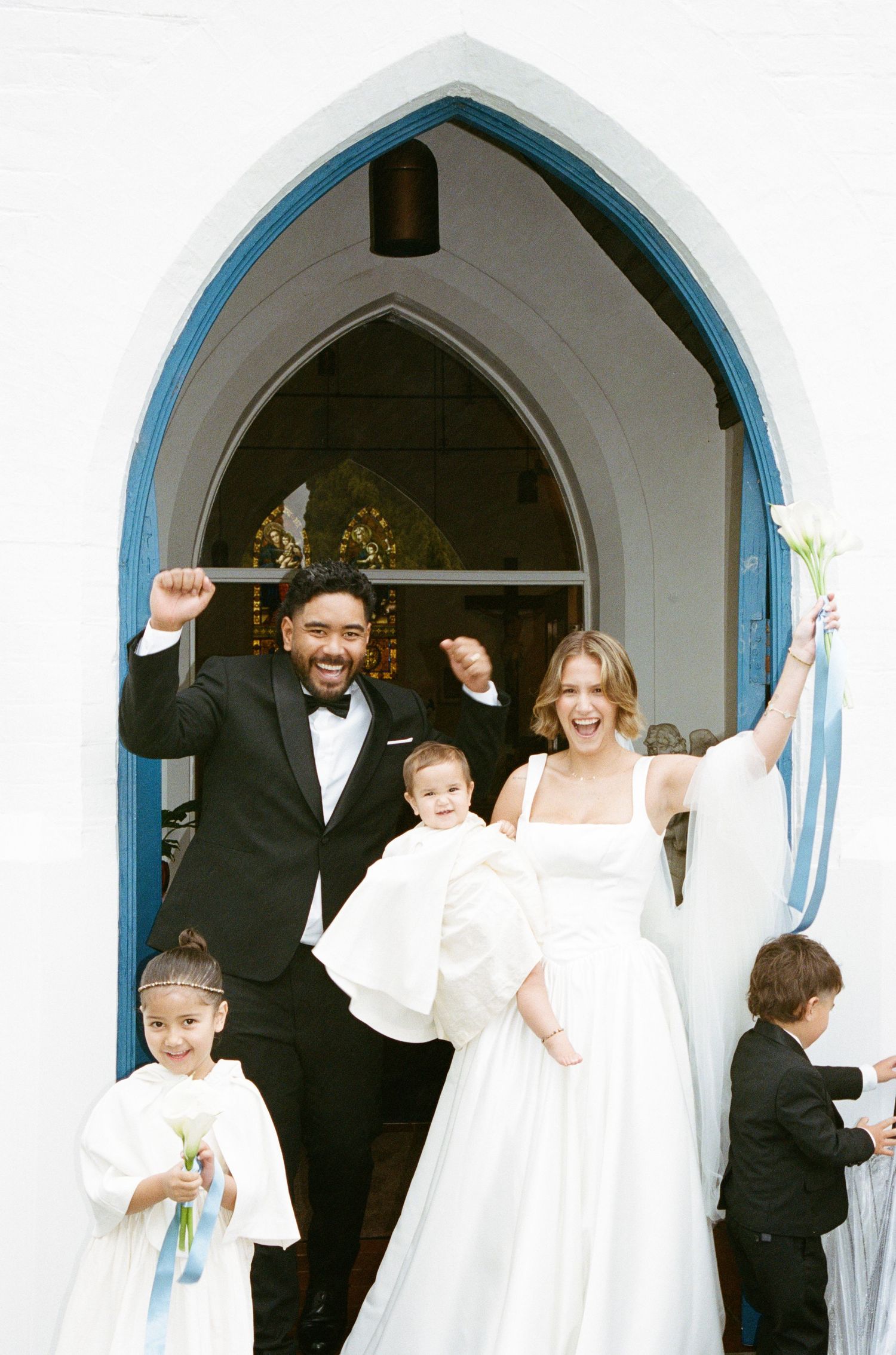 Wedding celebration under white gothic arches decorated with blue trim.