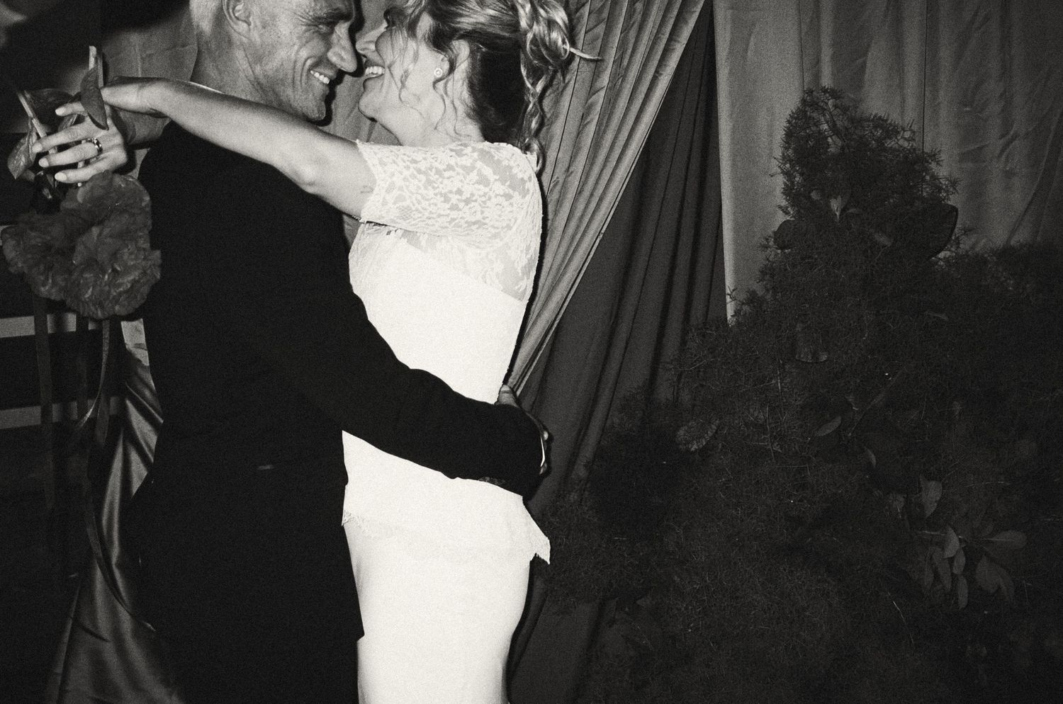 A couple shares a romantic embrace during a dance at what appears to be a formal evening event.