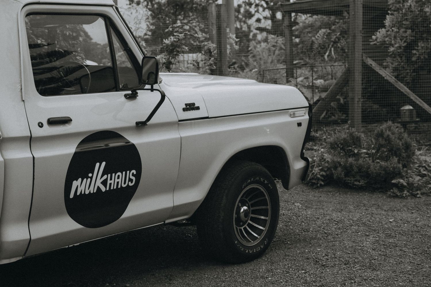 White delivery van with milk logo parked outside in black and white photography.