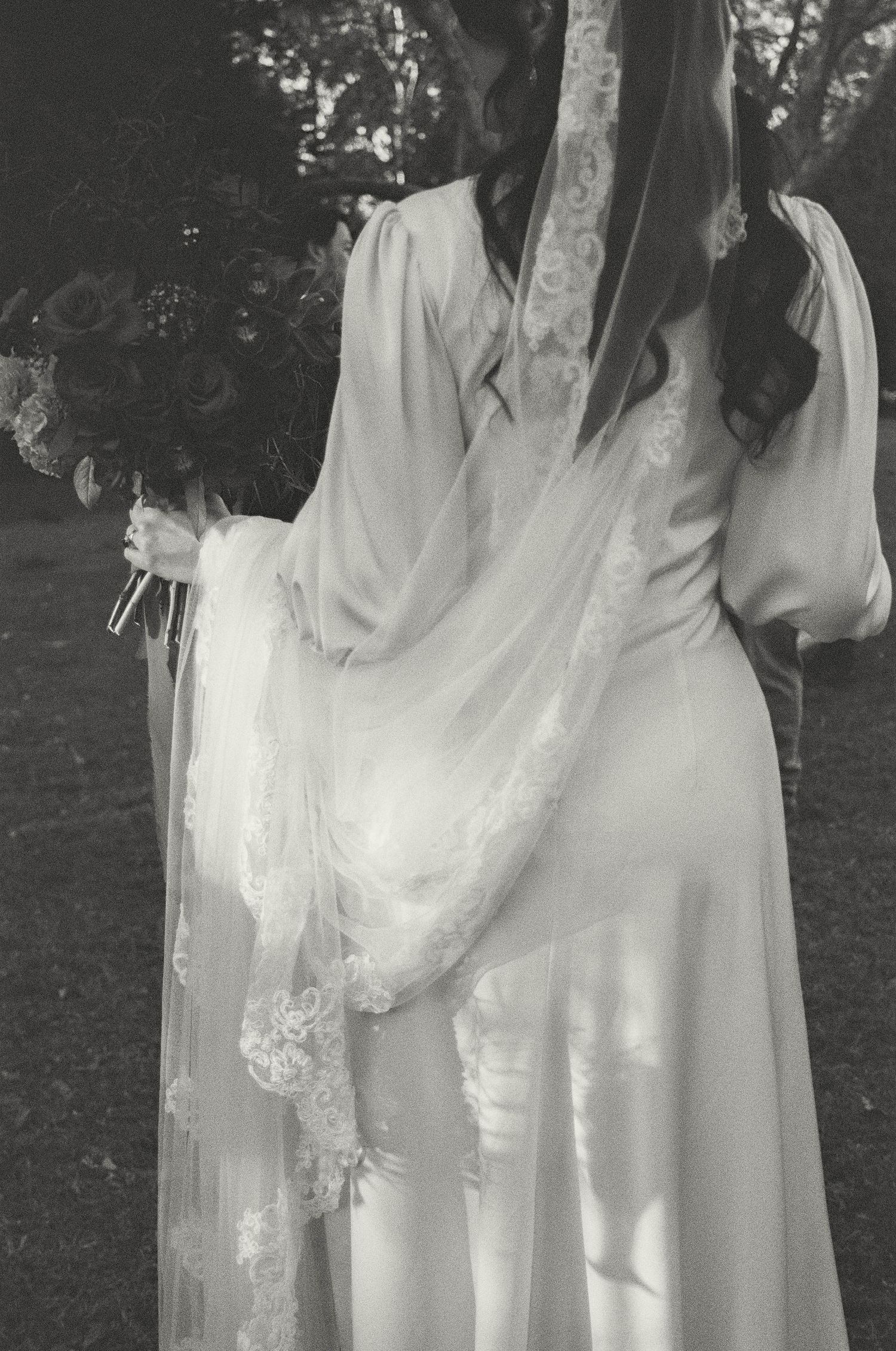 A dreamy vintage-style photograph showing flowing white lace fabric in a garden setting.