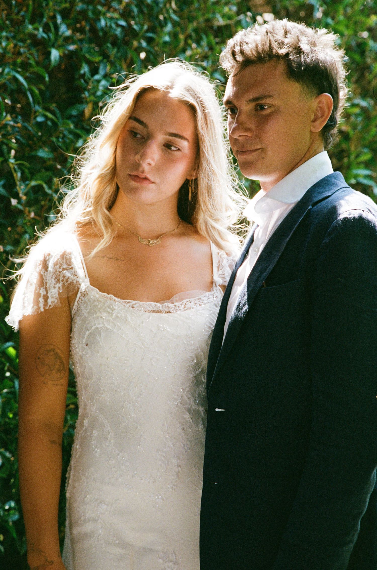 Romantic wedding portrait with couple embracing against a lush green garden background.