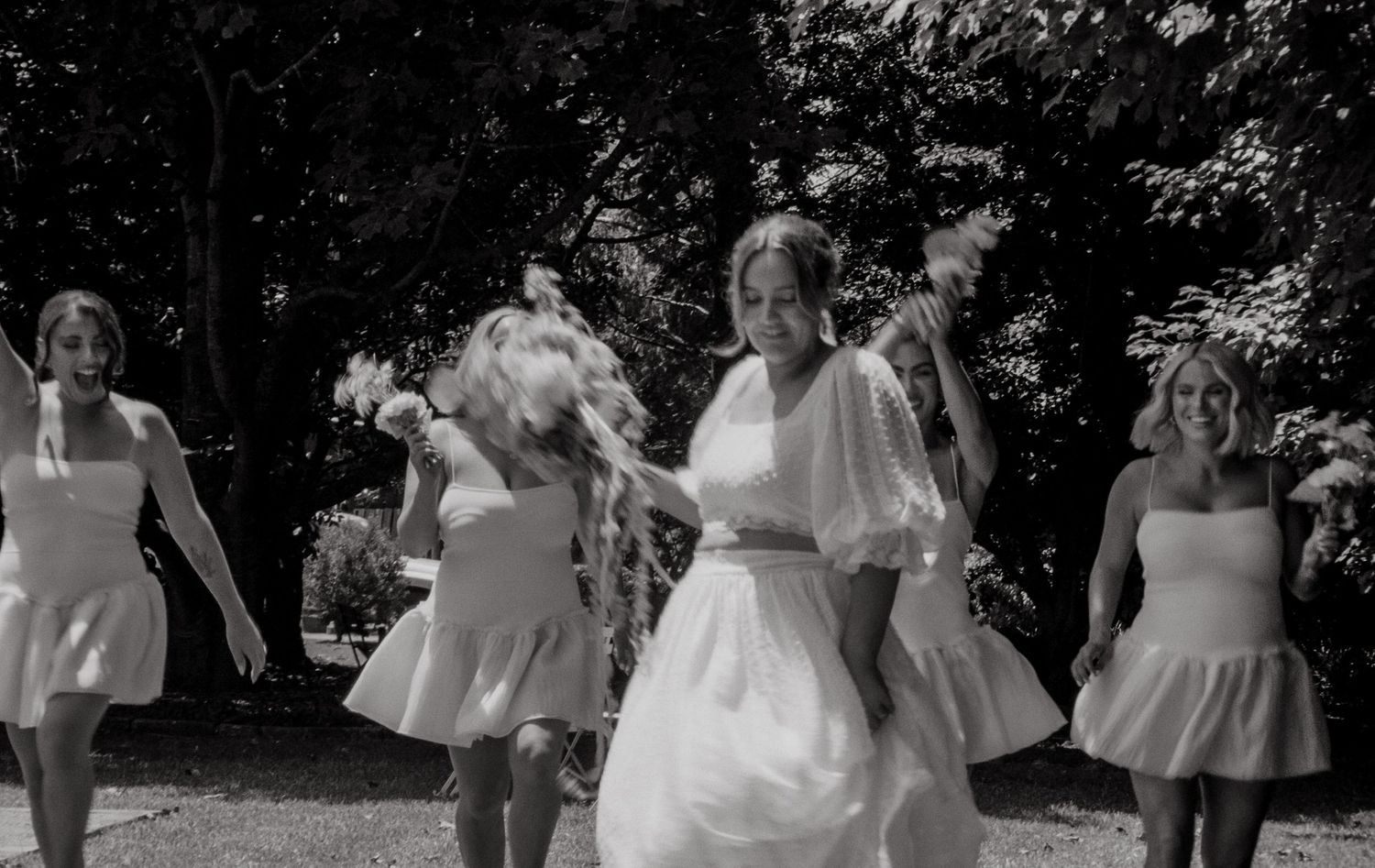 Black and white photographs show wedding guests dancing and celebrating at an outdoor reception celebration.