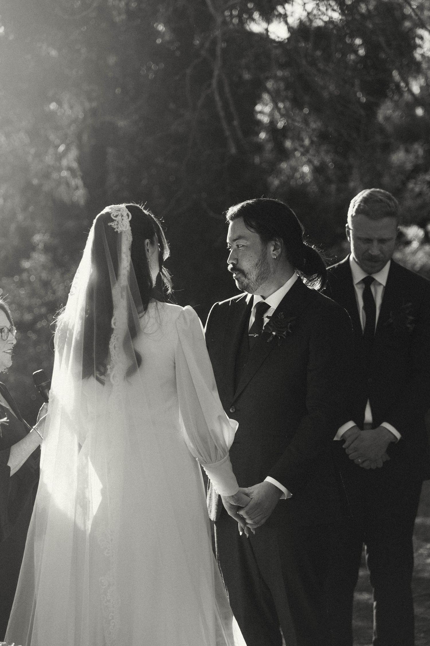 A wedding party walks together outdoors in black and white film style photography.