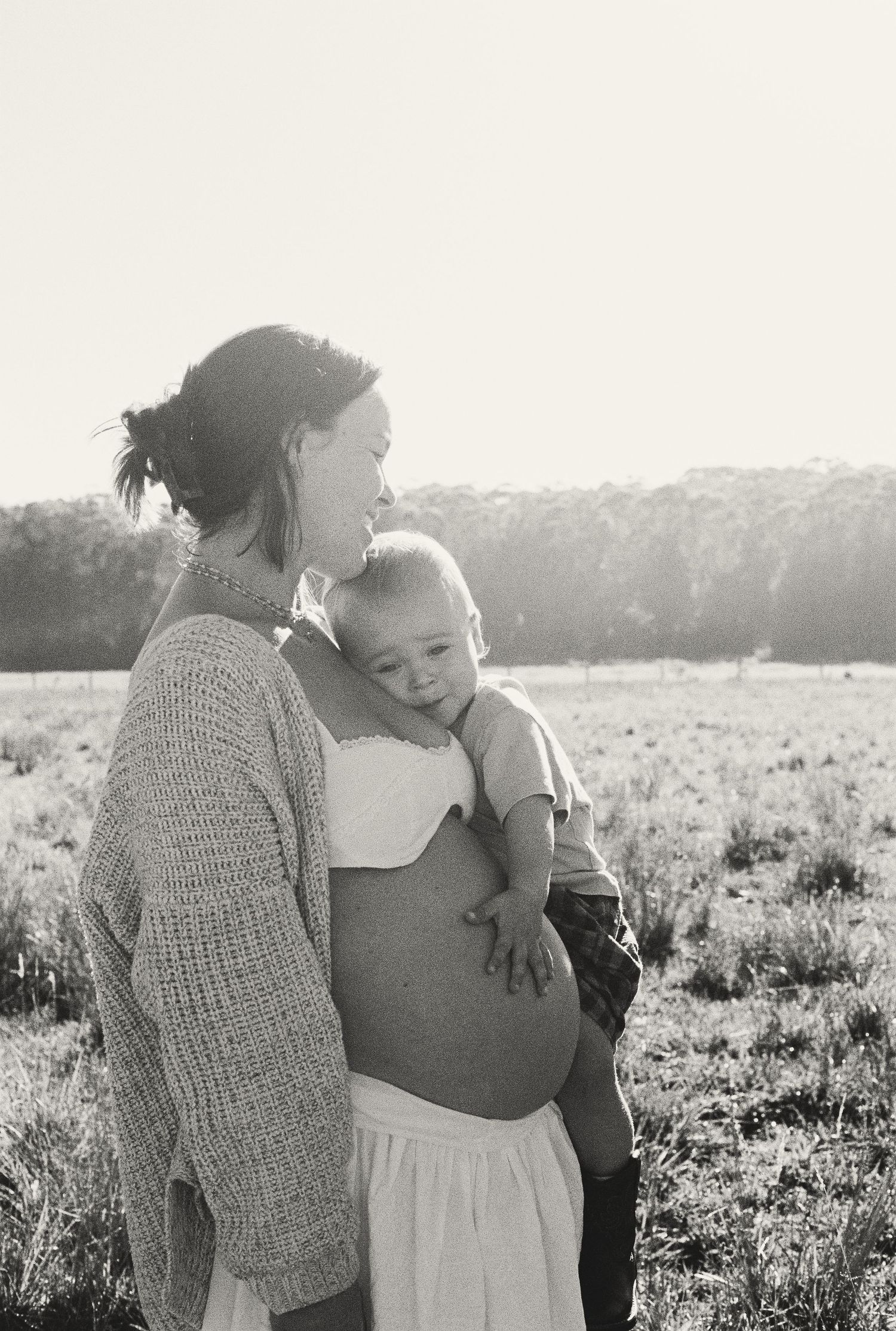 A tender black and white series of intimate moments captured between two people embracing in a sunlit field.