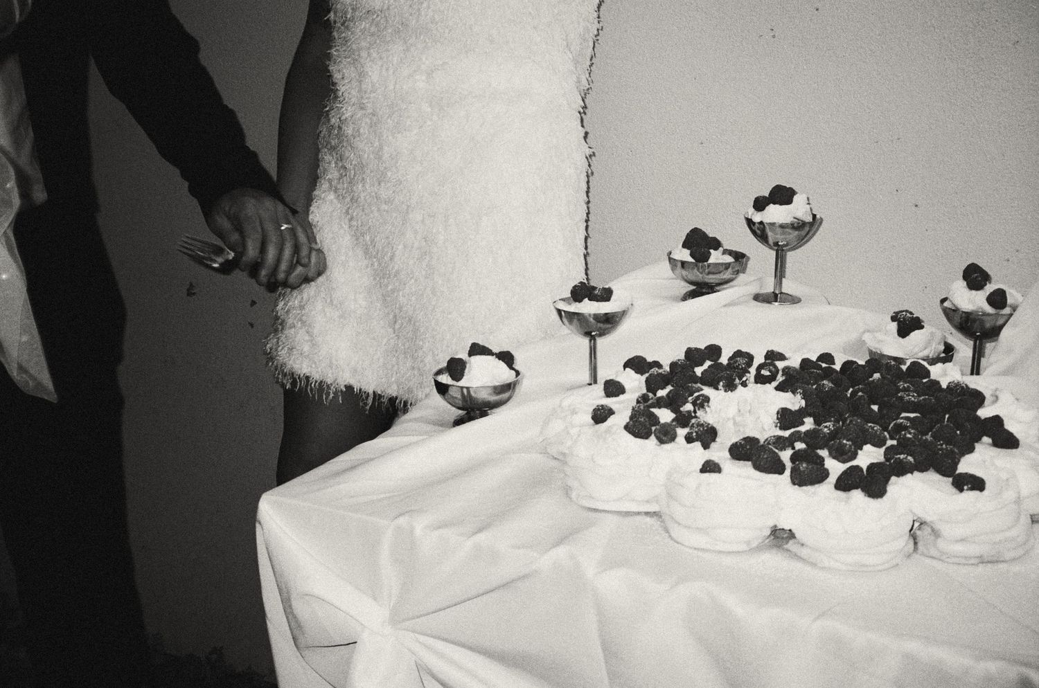 Black and white photo showing details of a wedding reception table with candles and scattered decorative elements.