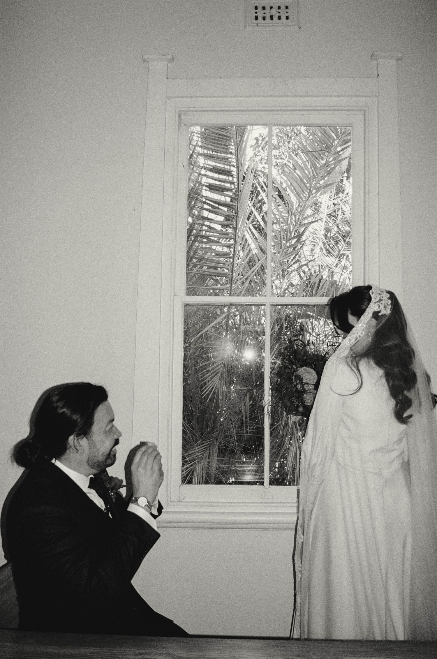 Multiple black and white photos showing someone peering through a window into the darkness while wearing a ghost costume.