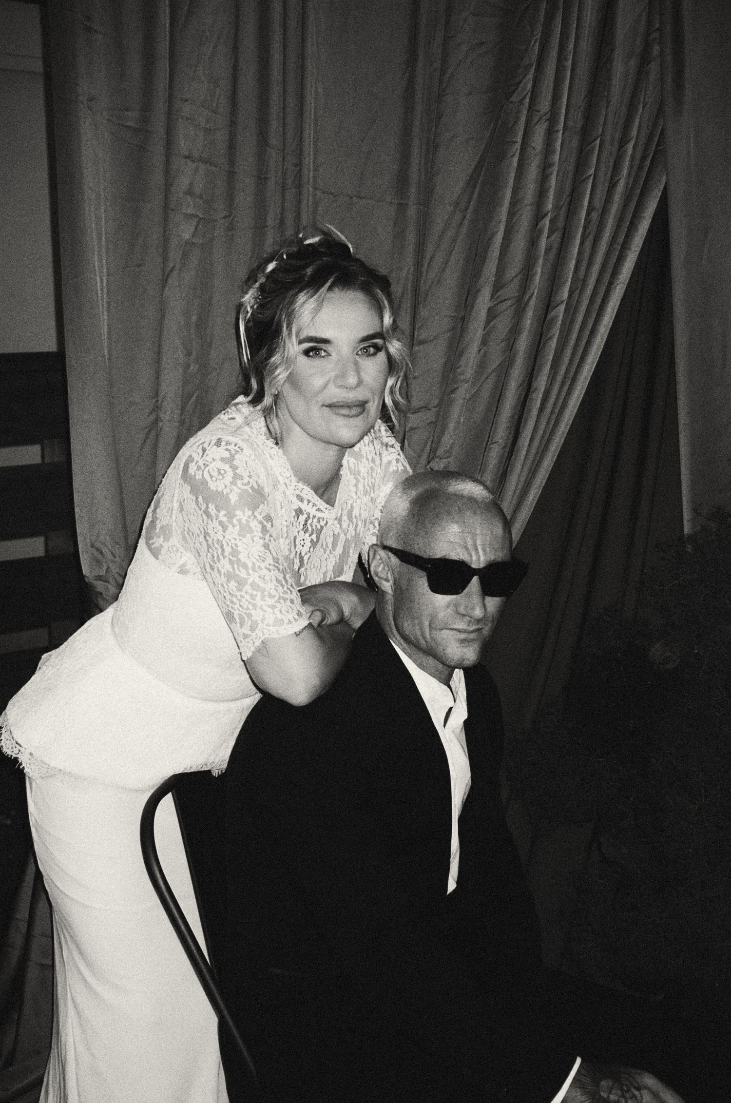 Elegant couple in formal attire share an intimate moment at what appears to be a black-tie event.