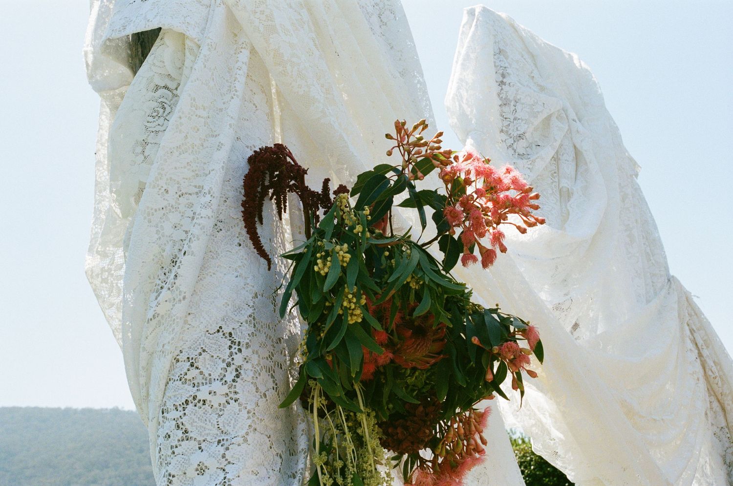 White lace curtains and floral arrangements create an elegant wedding backdrop.