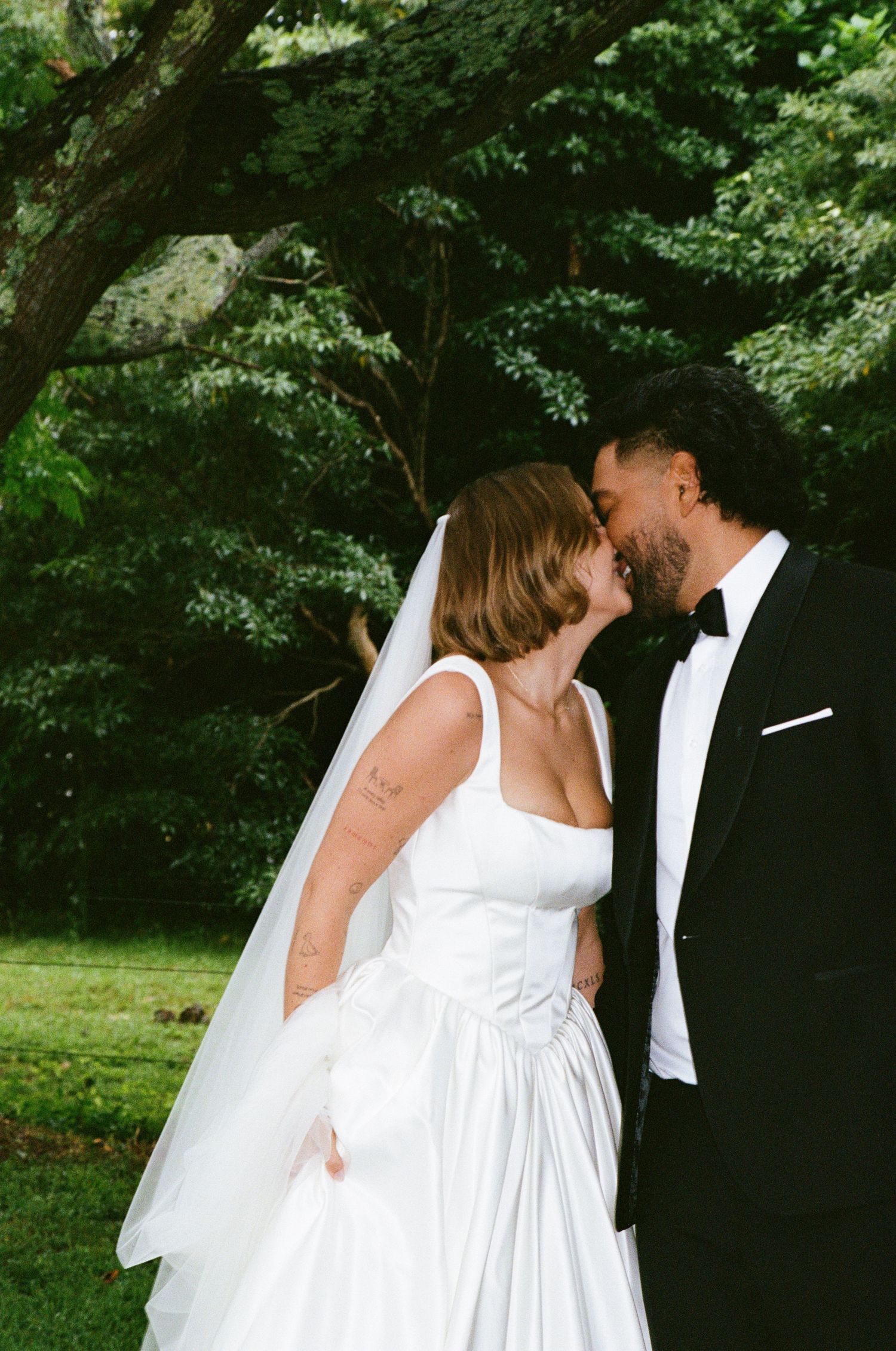 A romantic wedding portrait showing a tender moment between newlyweds in a garden setting.