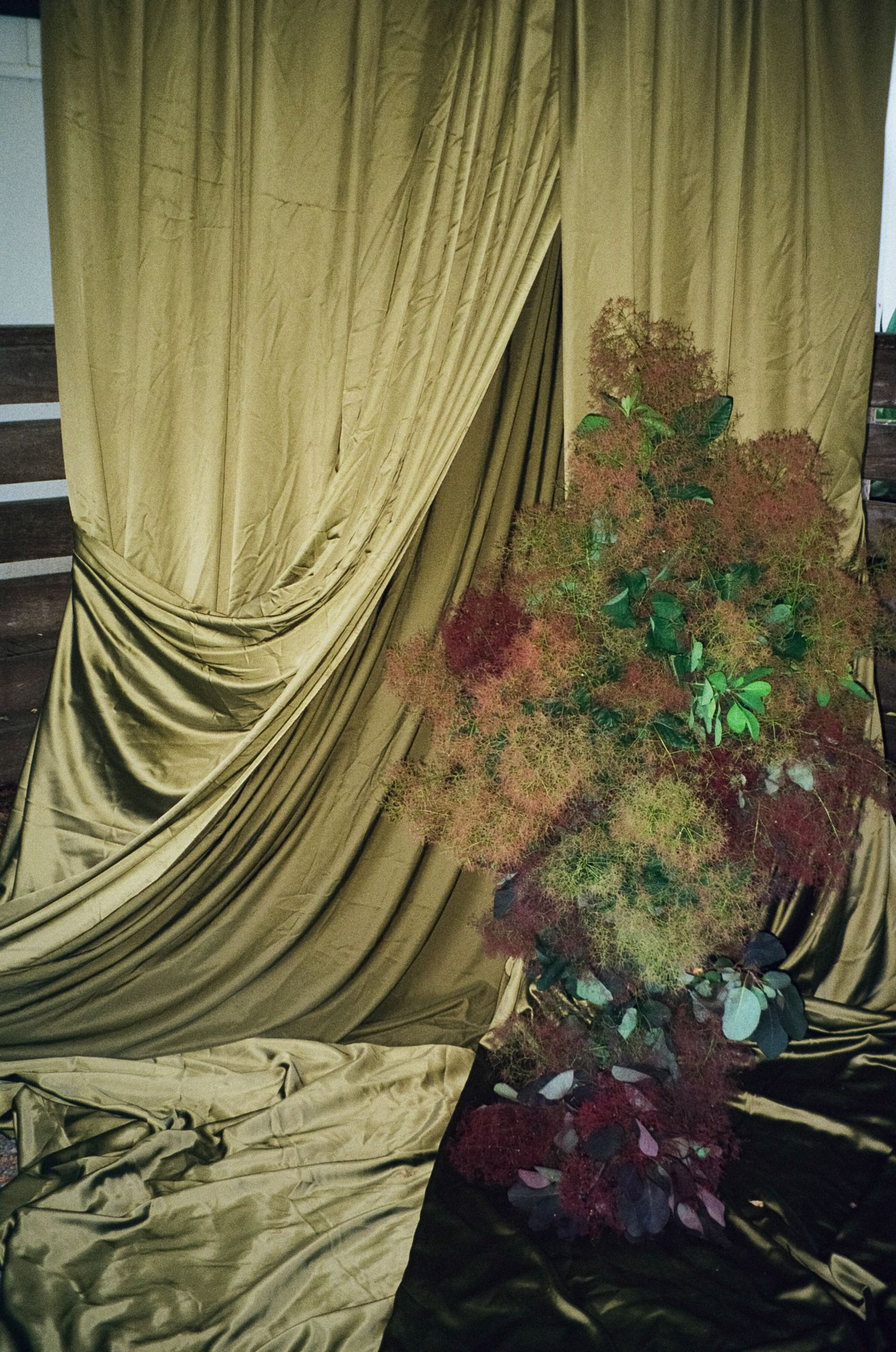 A sequence showing dark red and green floral arrangements against draped beige fabric backdrop.