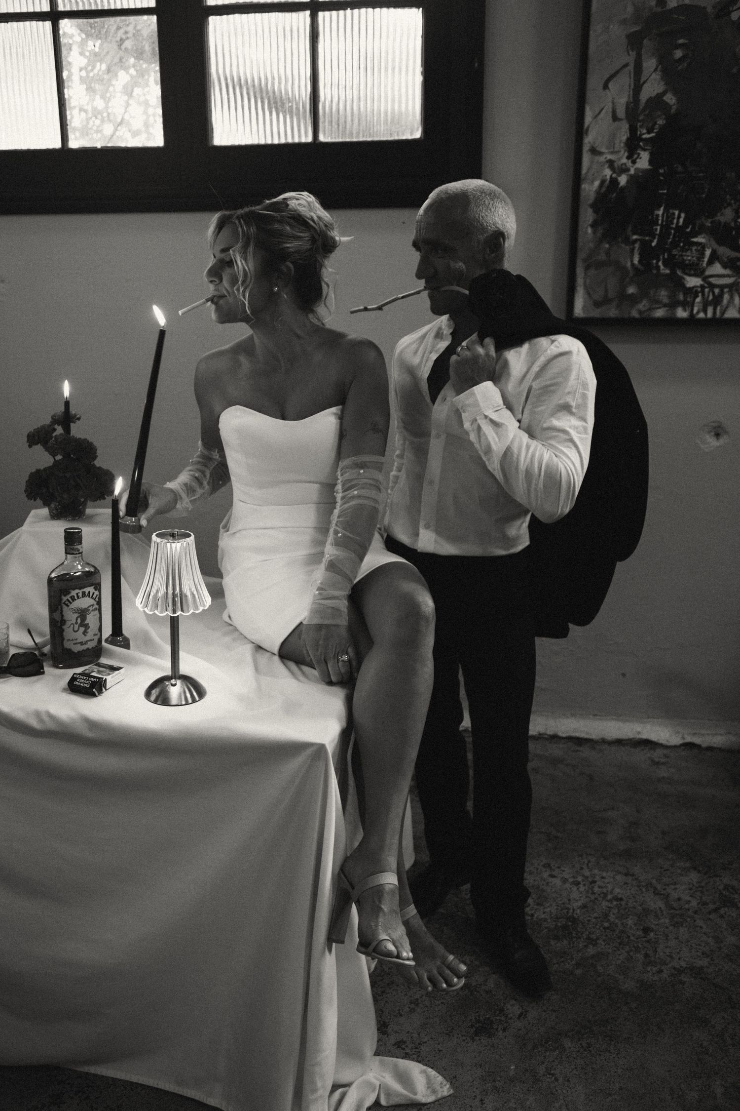 Black and white photo of wedding guests gathered around an elegantly set table with candles.