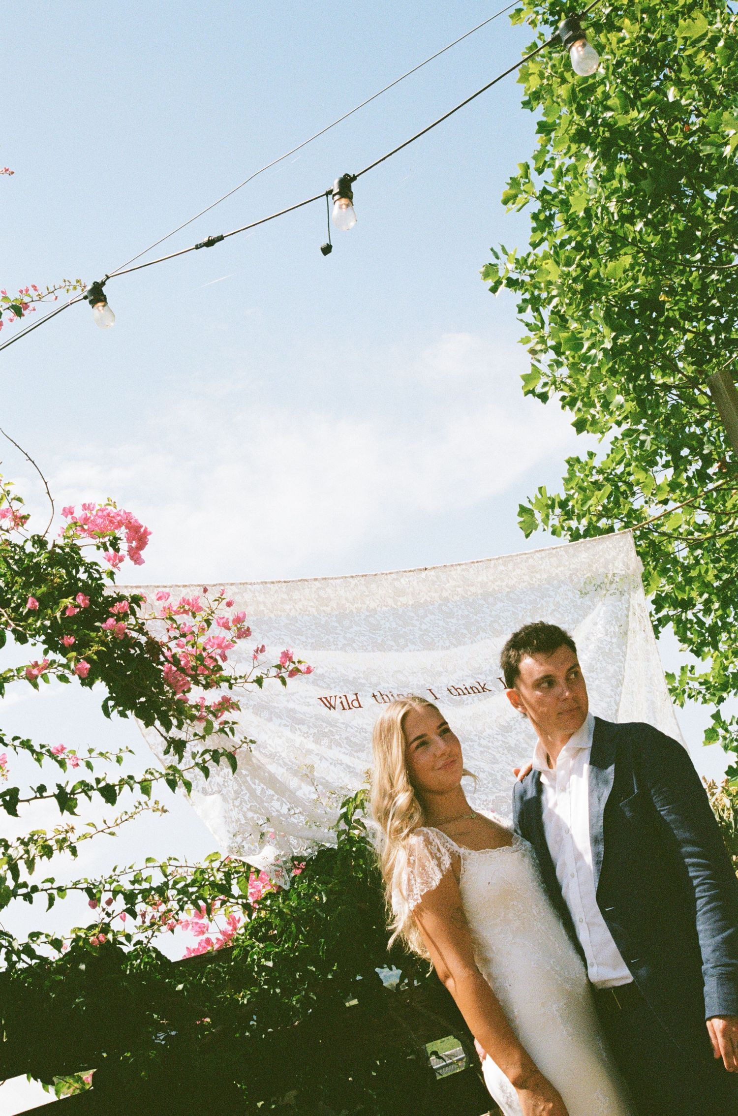 A romantic outdoor wedding ceremony with string lights and pink flowers decorating the space.