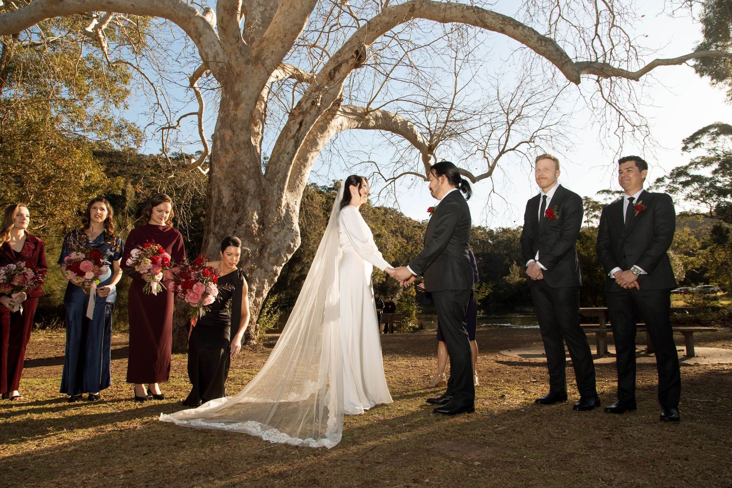 Wedding ceremony under majestic oak trees with guests gathered in outdoor setting.