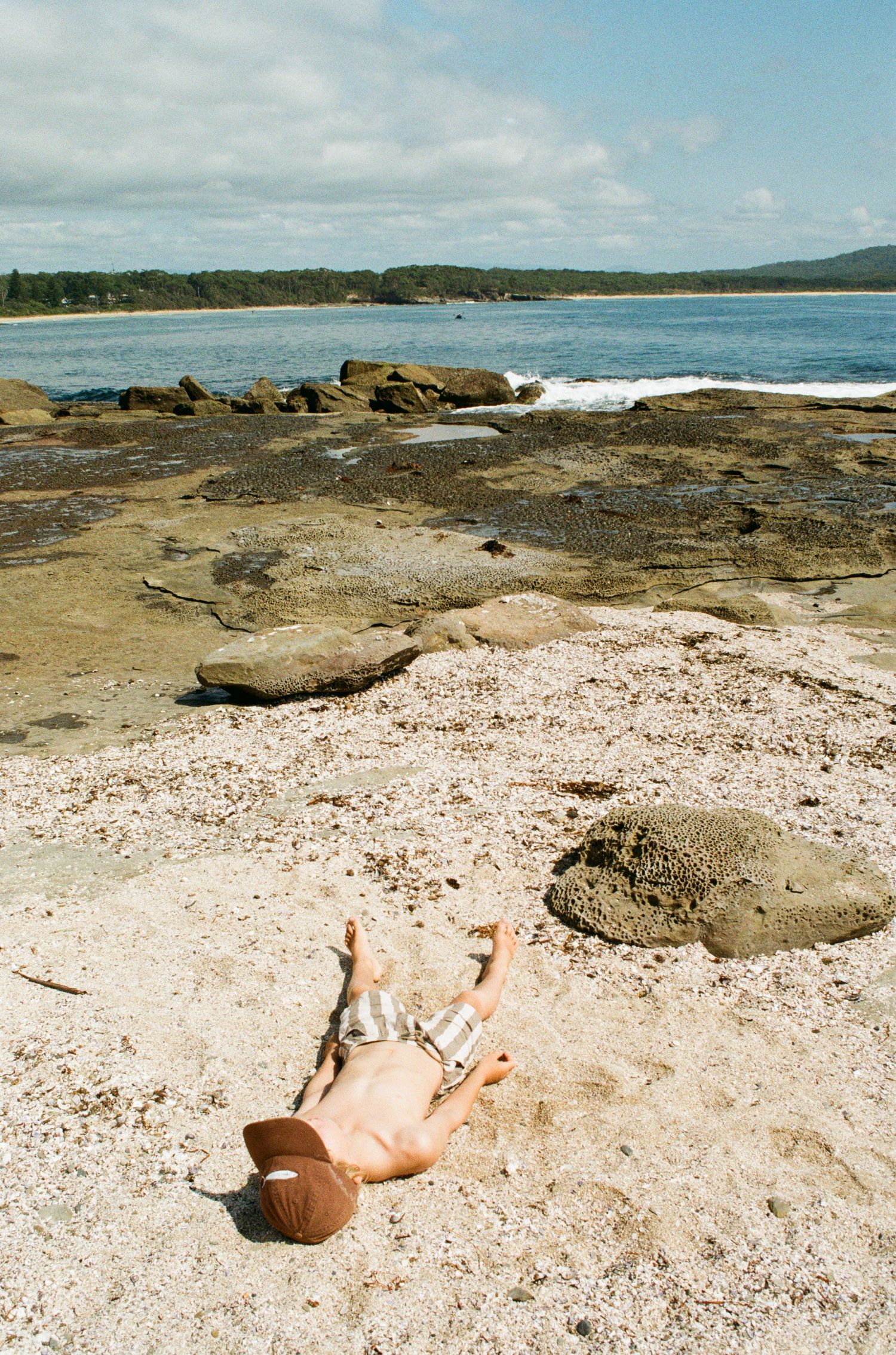A series of photos showing a sandy beach with rocks and ocean waves along a scenic coastline.