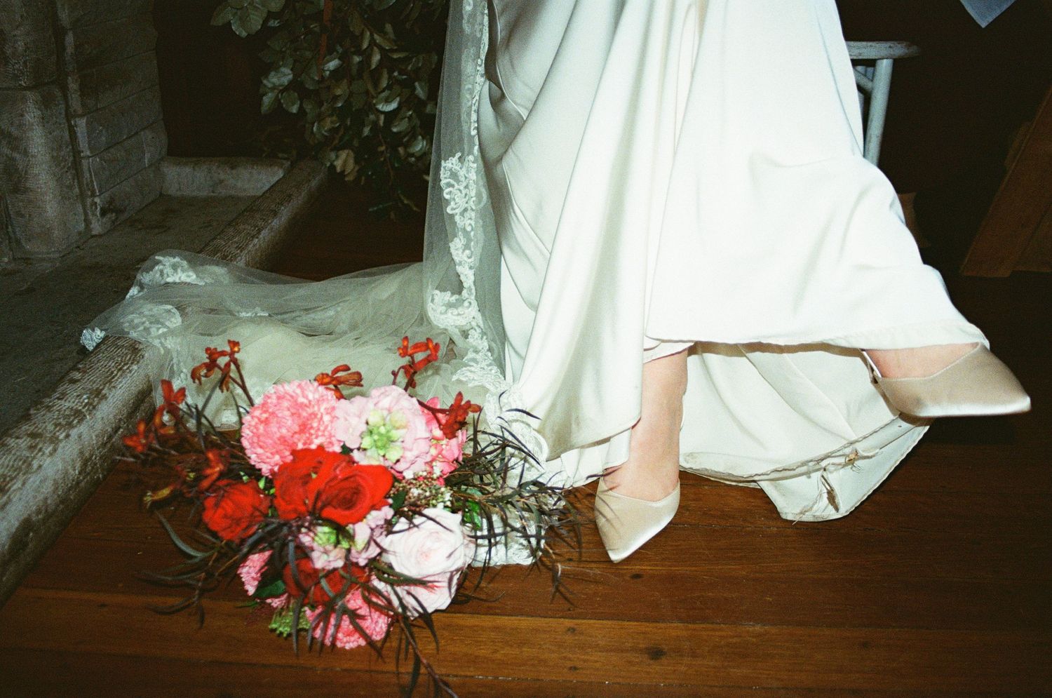 White bridal gown details with soft pink and coral floral arrangements cascading along the bottom of the dress.