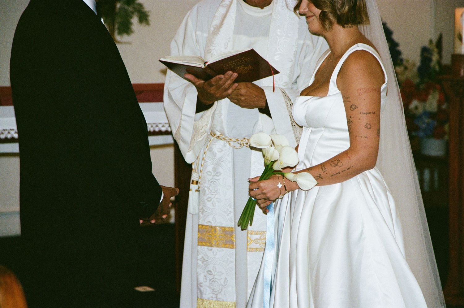 Wedding ceremony participants in white attire gathered around signing documents.