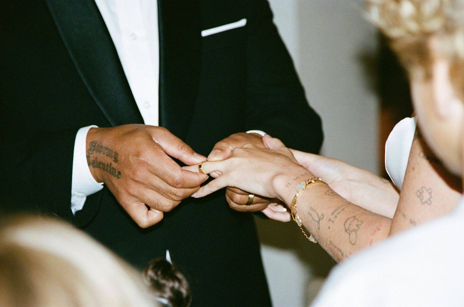 Hands of wedding couple signing marriage documents with witnesses at a ceremony.