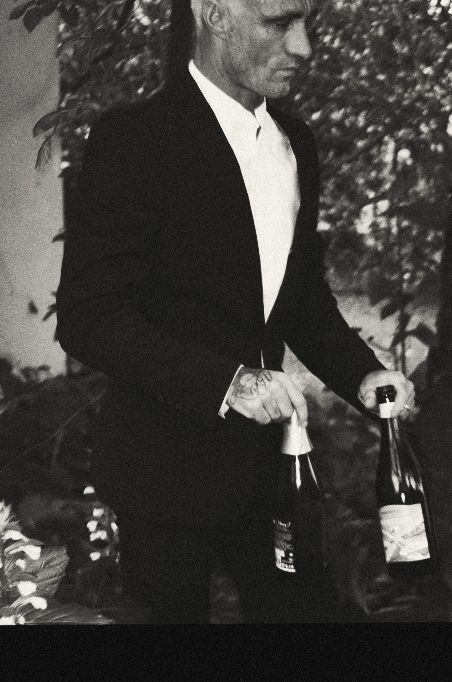 Figure in black suit opening bottles at an elegant event.