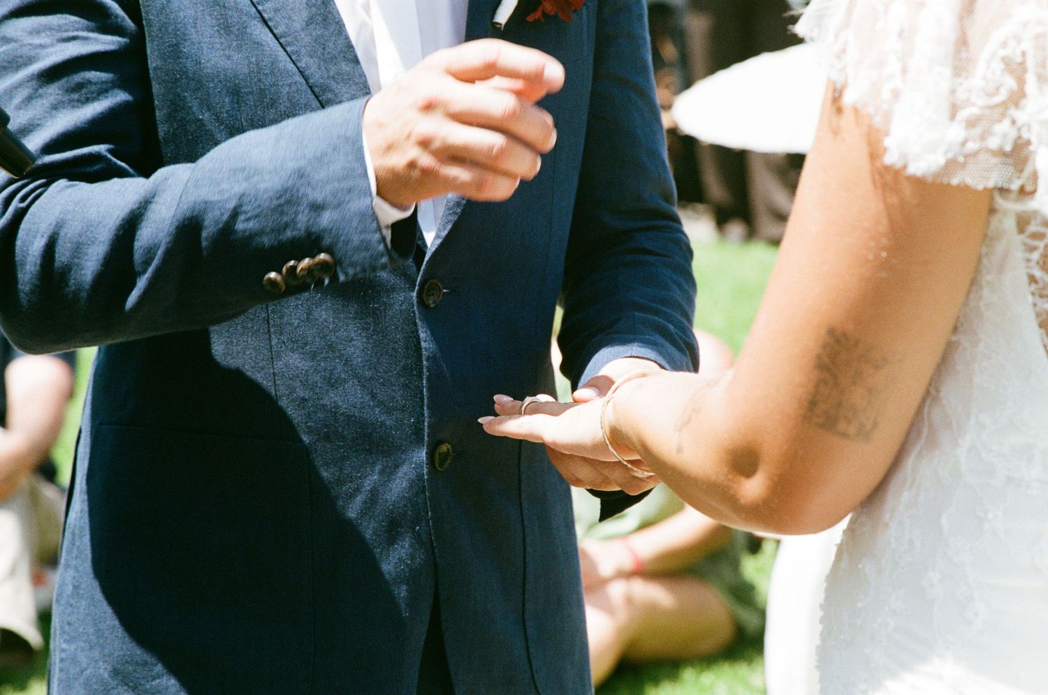 Close-up details of formal attire and hands during a wedding ceremony.