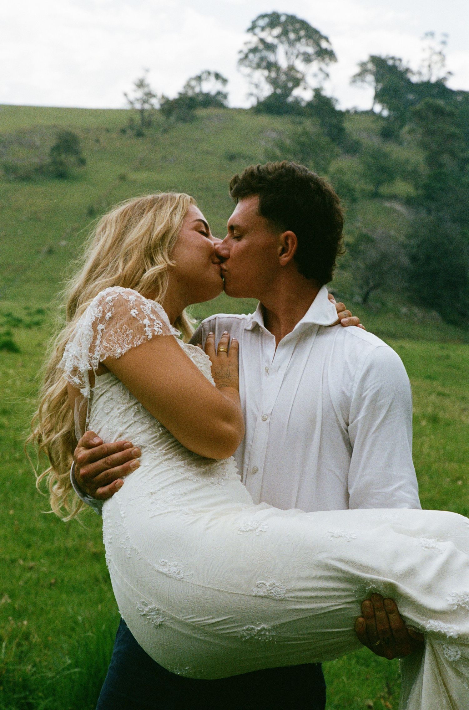 Couple shares romantic moments on a scenic hillside during their wedding photoshoot.