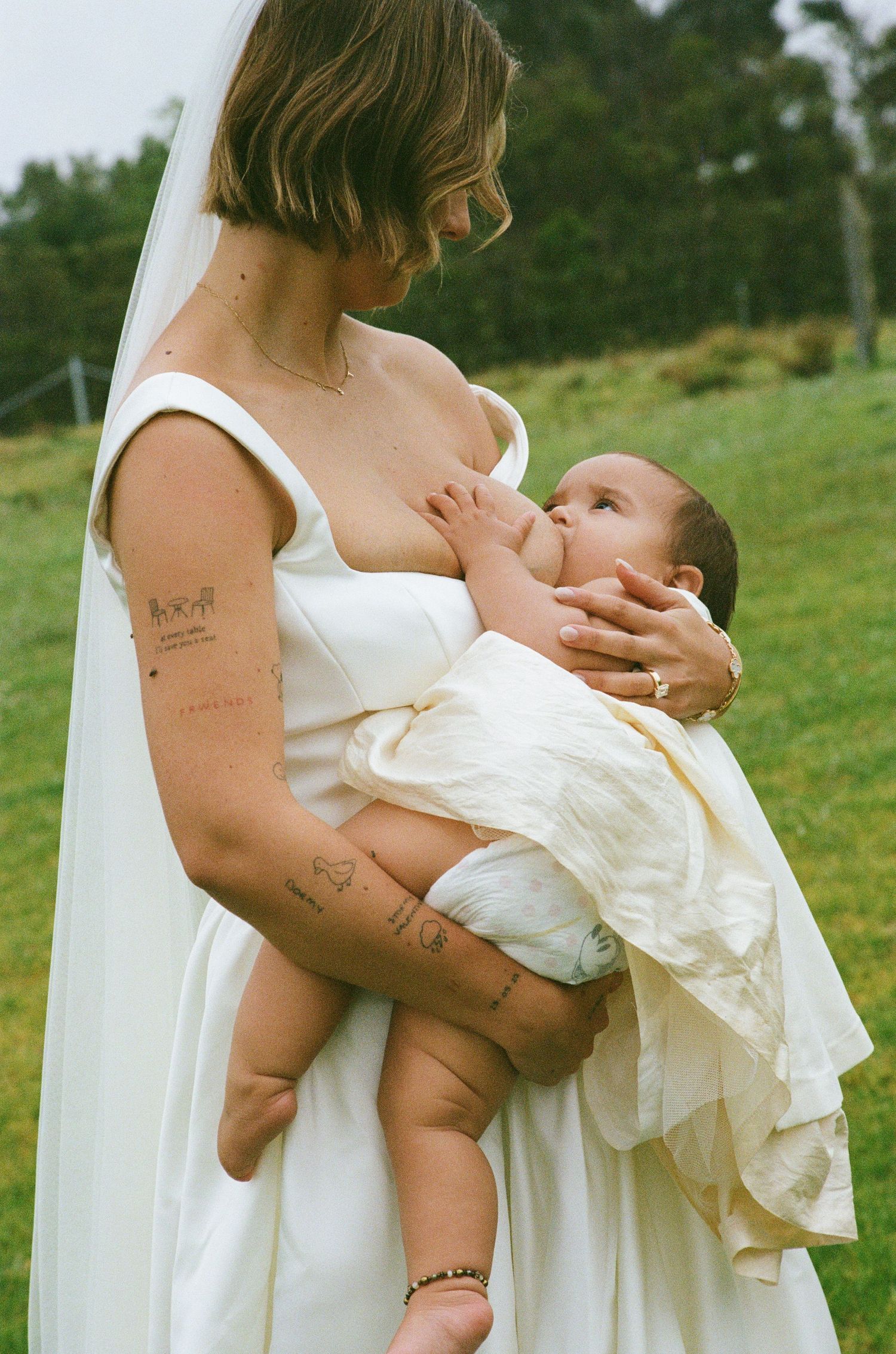 A tender moment of breastfeeding captured outdoors in a grassy field.