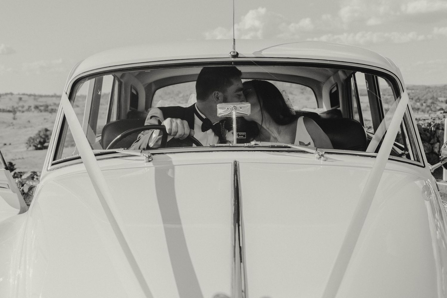 A close-up view of a classic Volkswagen Beetle's front hood and windshield shot in black and white.