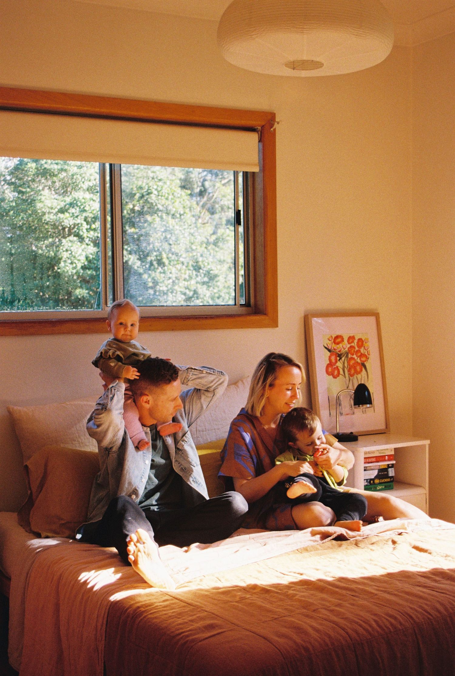 Four sequential images showing a couple relaxing on a brown bed in a sunlit room with windows and colorful decor.