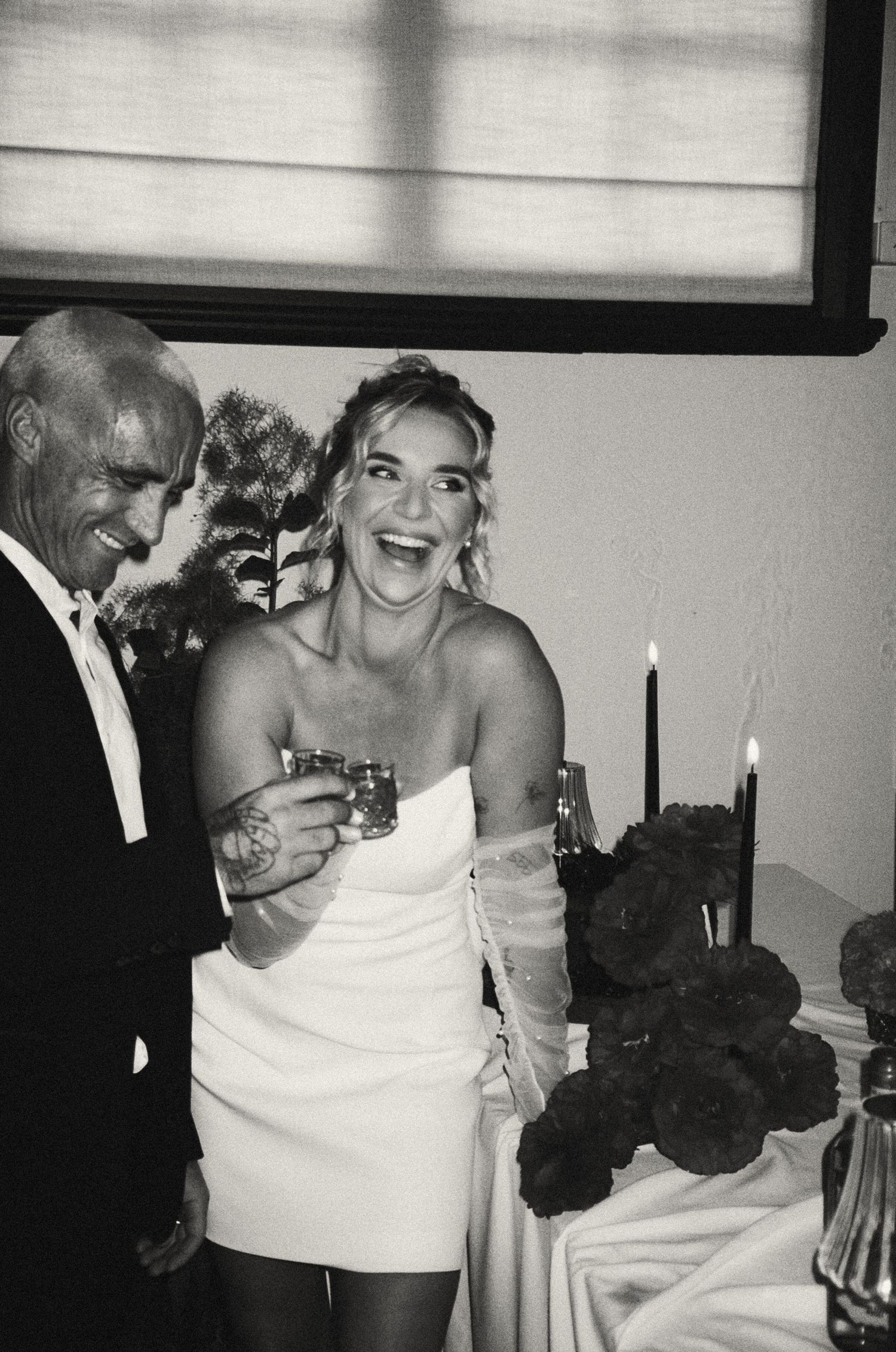 A joyful candid black and white moment between a couple at a celebration.