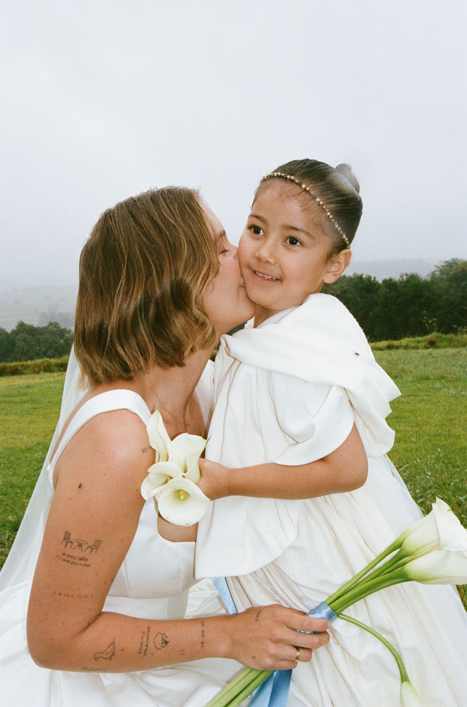 A touching moment between two people embracing in a field with white calla lilies.
