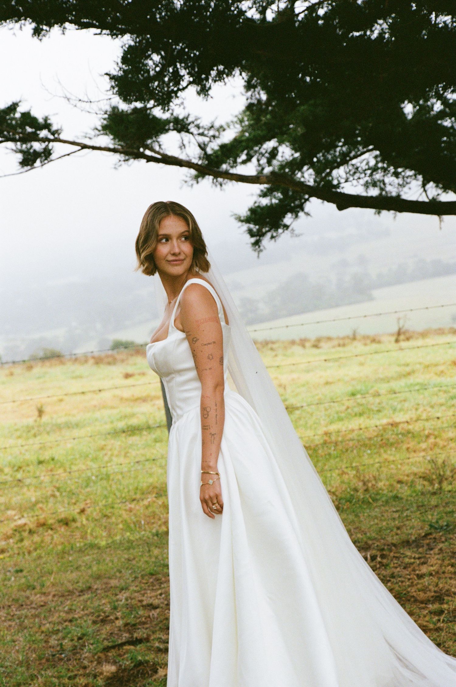 A flowing white wedding gown billows in the breeze against a scenic mountain landscape backdrop.