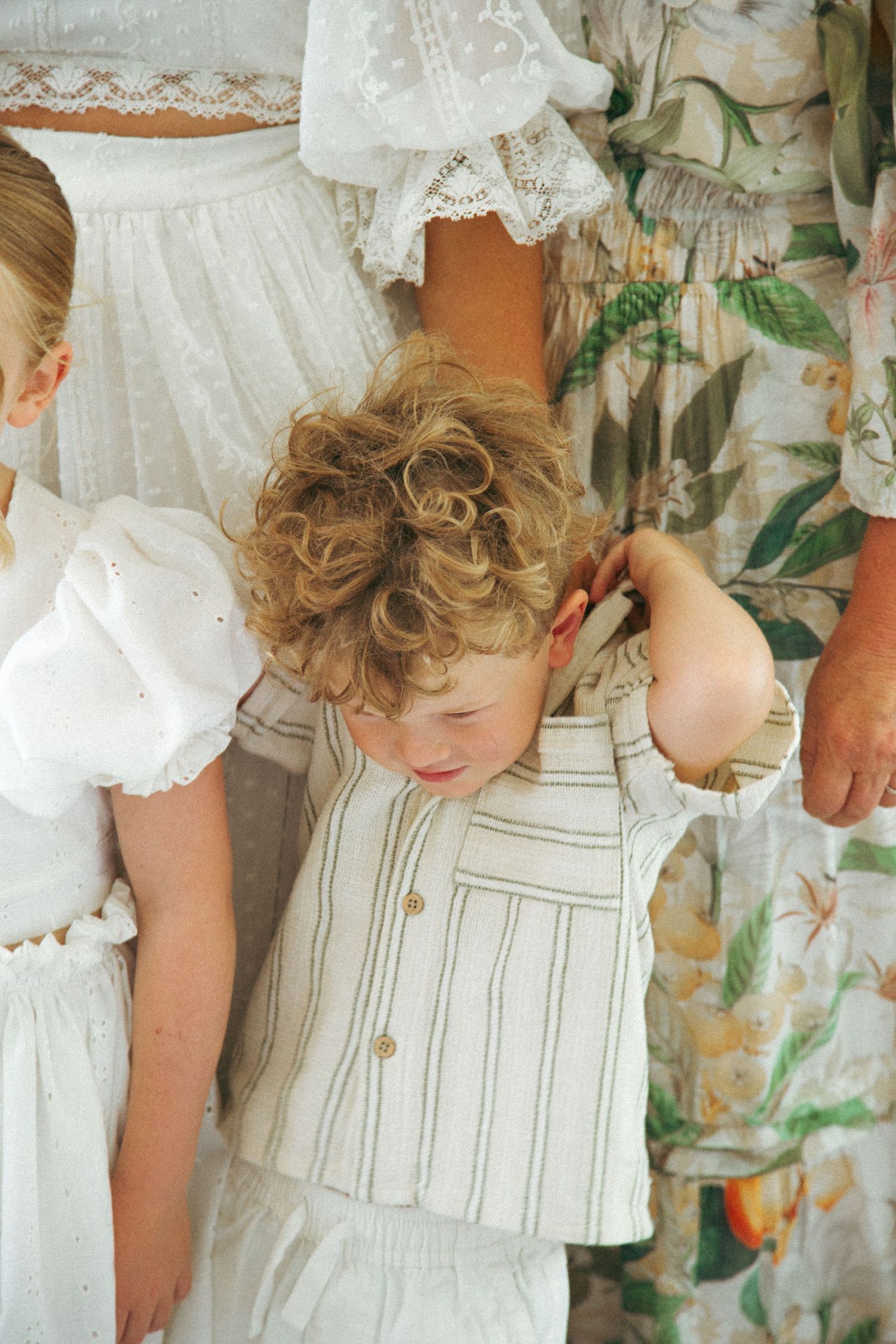 Close-up detail of white lace dresses and vintage-style children's clothing against a floral backdrop.