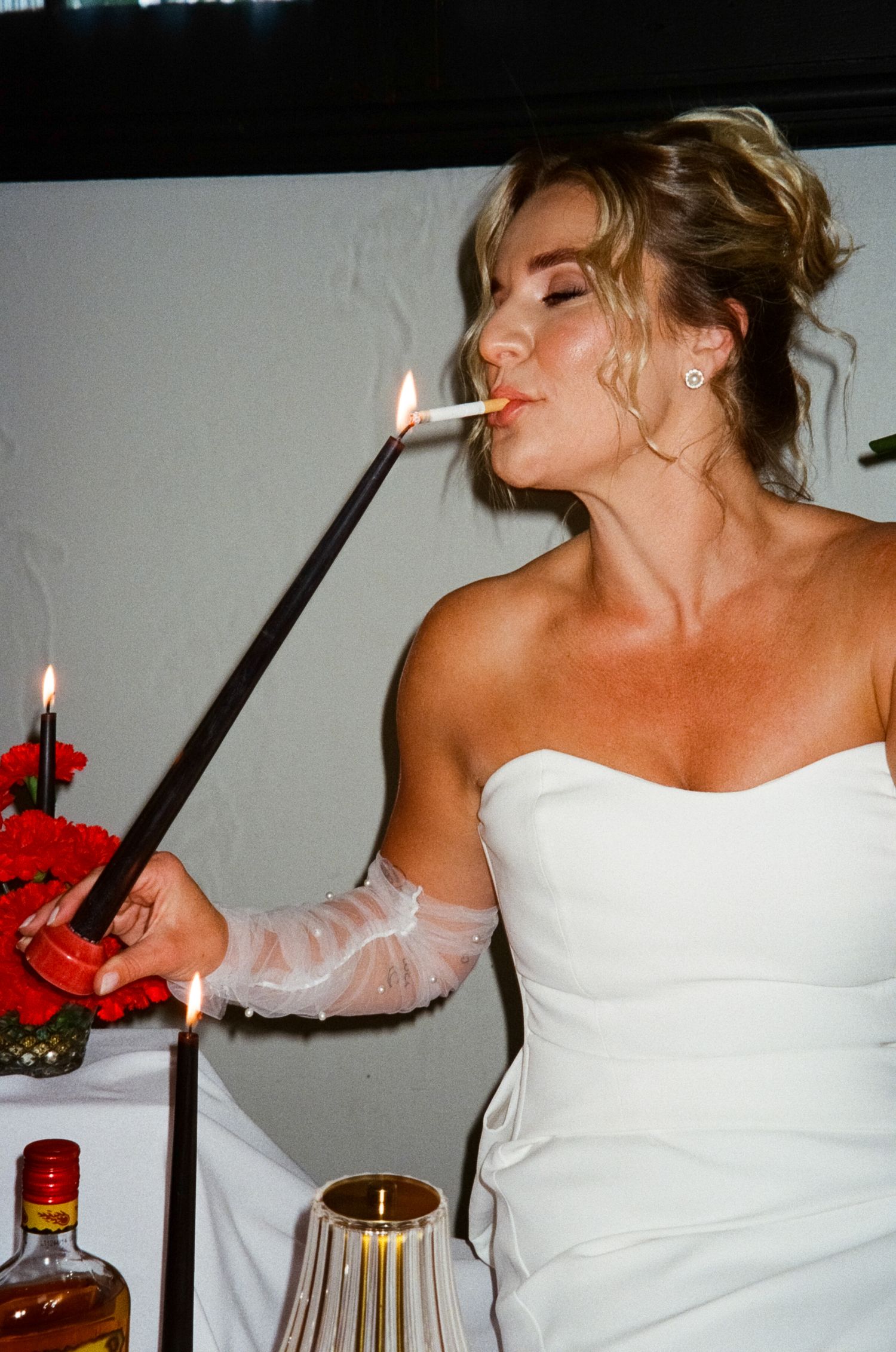 White gown clad figure enjoying drinks and festivities during an elegant celebration.