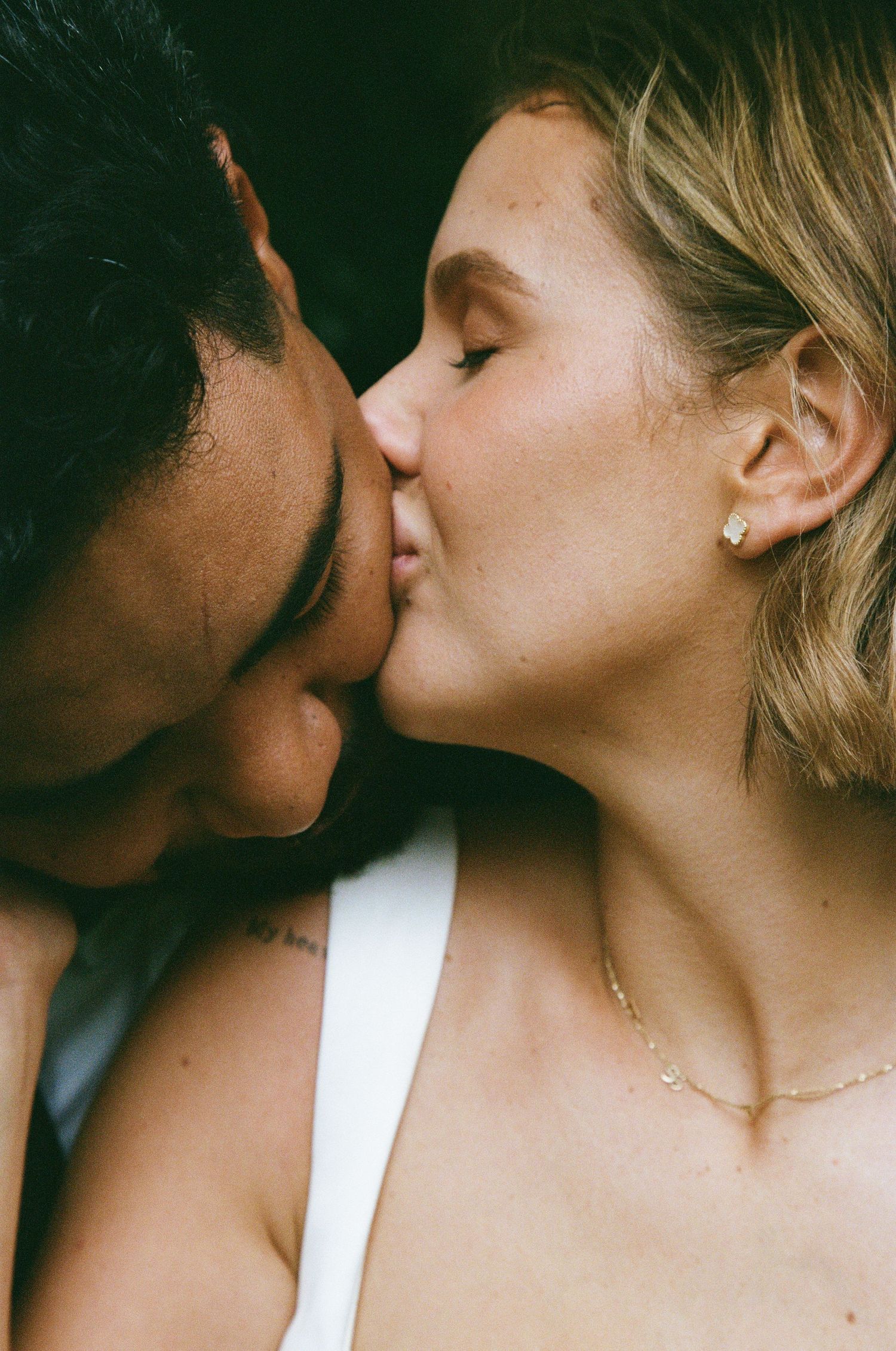 A romantic close-up portrait captures a tender kiss between newlyweds.