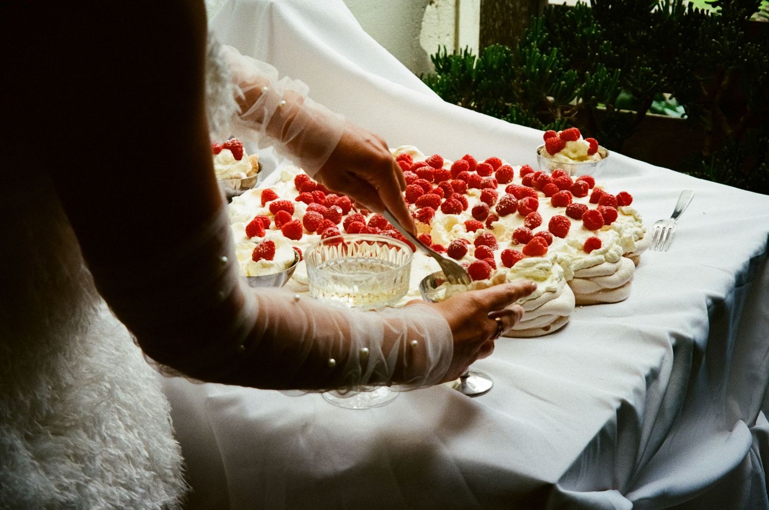 Champagne glasses and rose petals arranged on elegant white tablecloth at wedding reception.