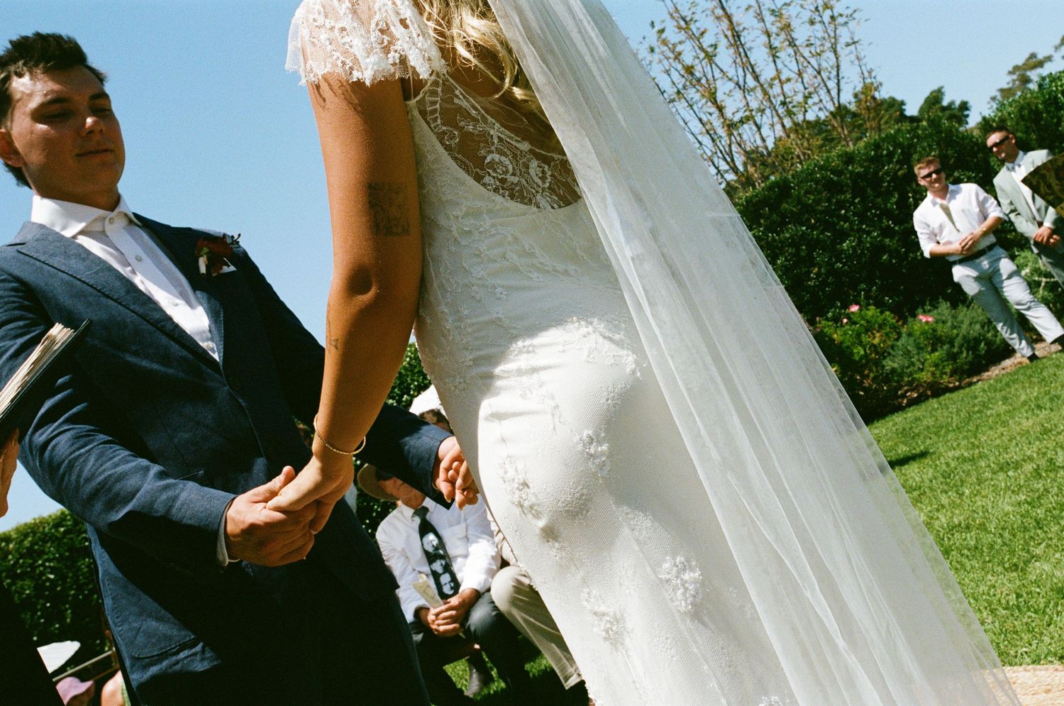 Wedding ceremony taking place outdoors with white fabric draping and mountain scenery.