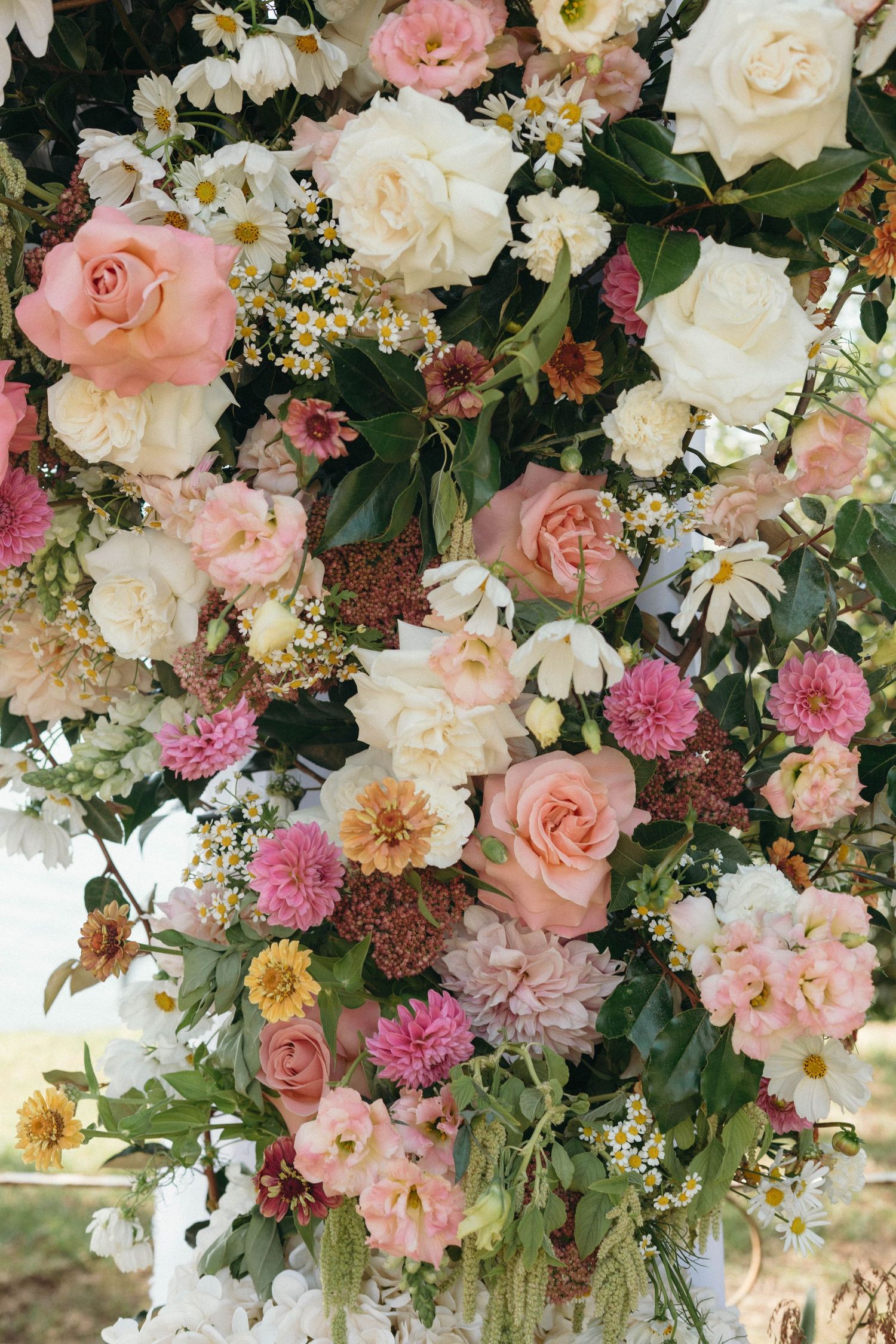 Lush floral arrangement with pink and white roses, carnations, and greenery cascading down in an elegant display.
