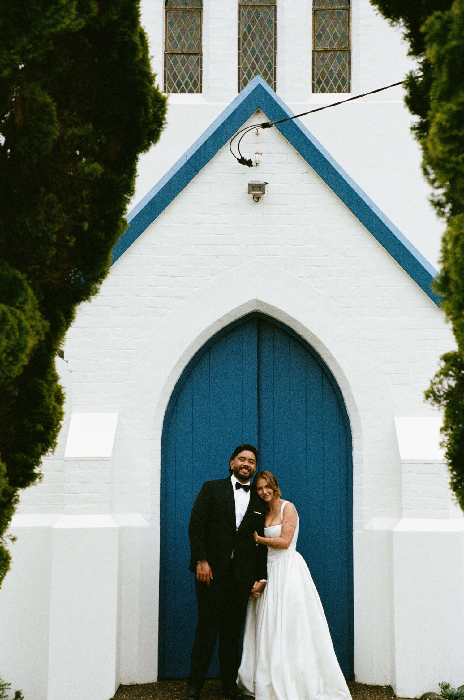 A classic church exterior with white walls and distinctive blue arched doors.