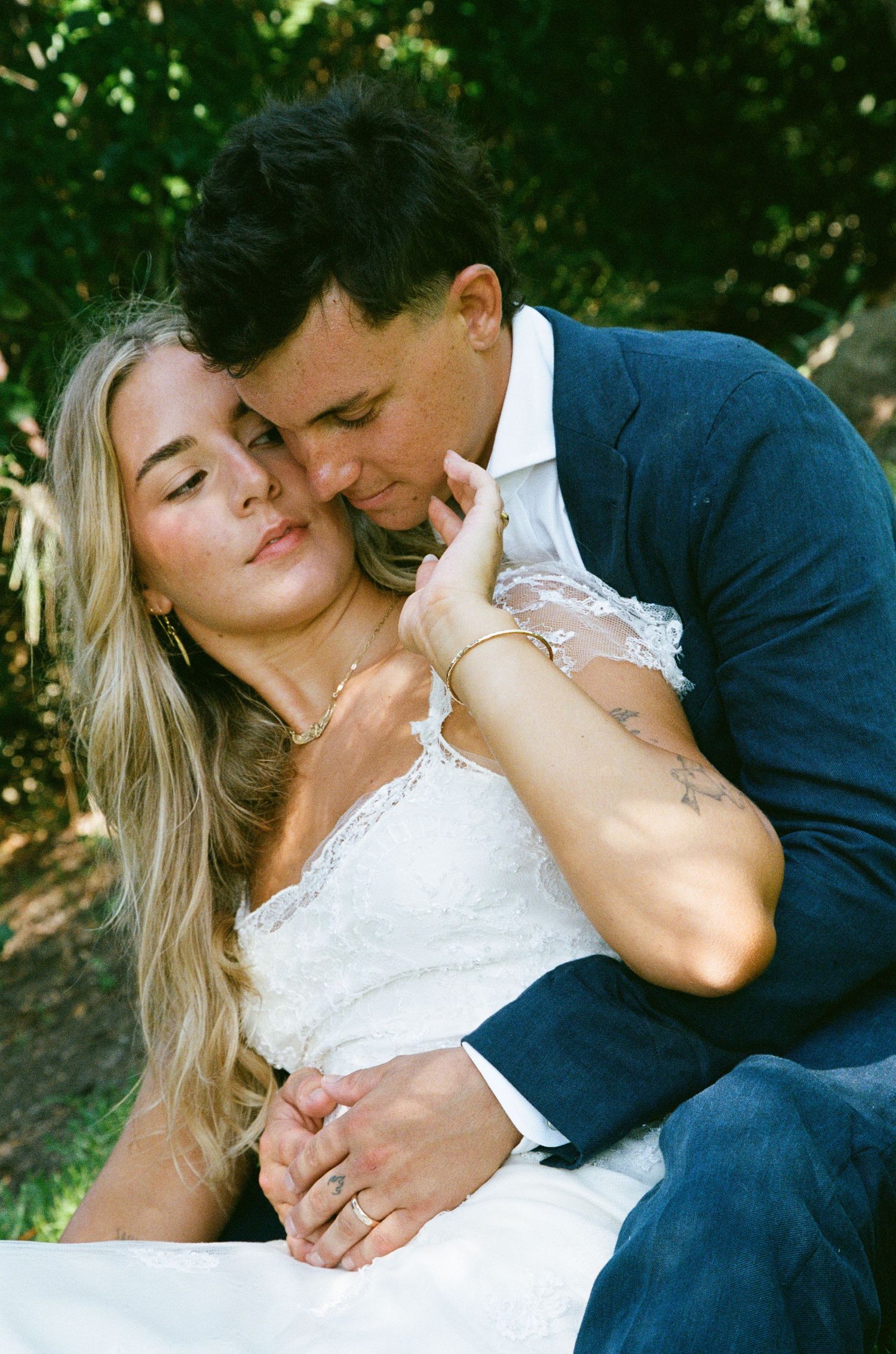 Romantic wedding couple sharing an intimate moment outdoors in formal attire.
