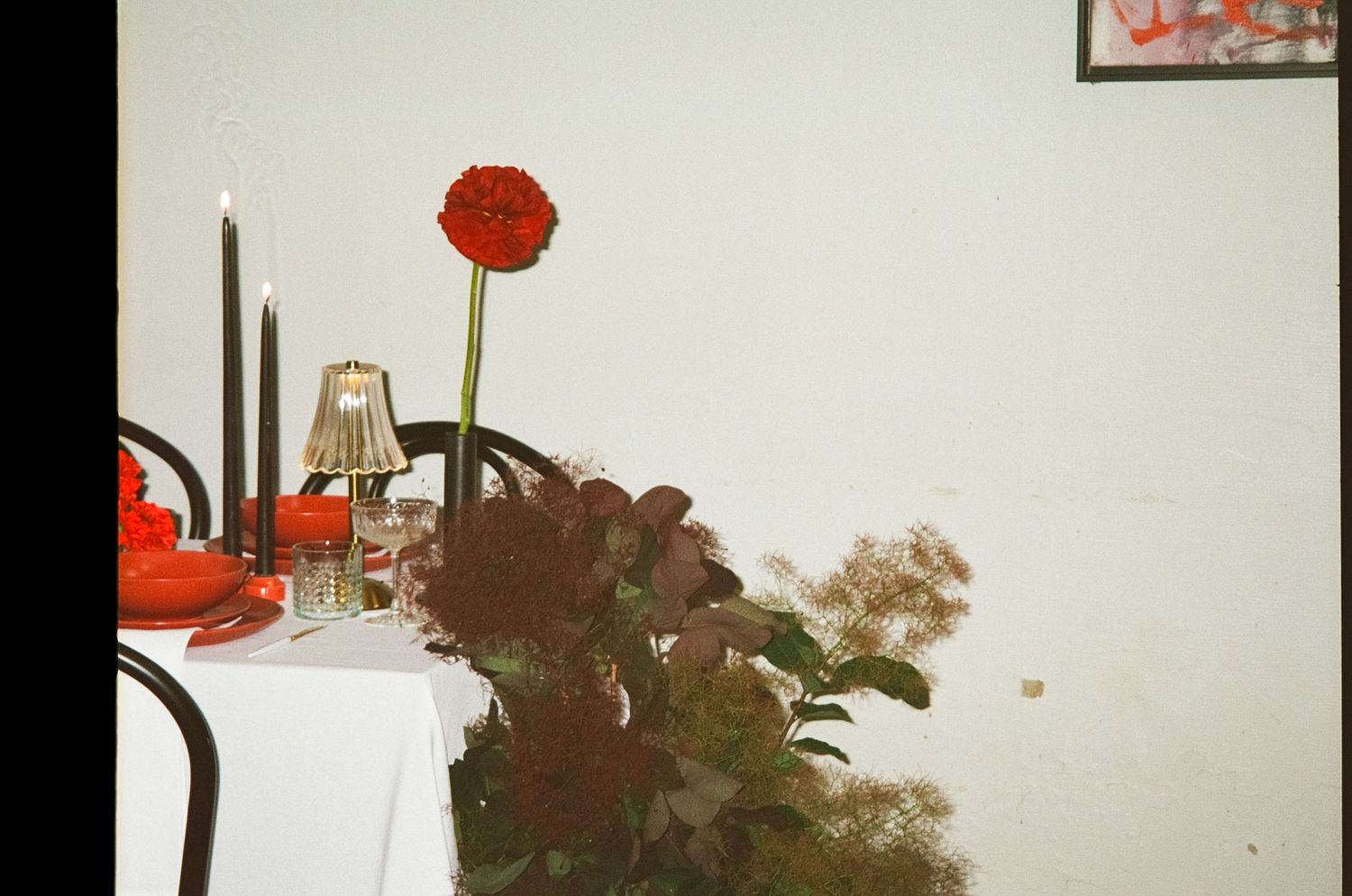 A series of red floral arrangements line up along a white wall, creating an elegant display of crimson blooms.